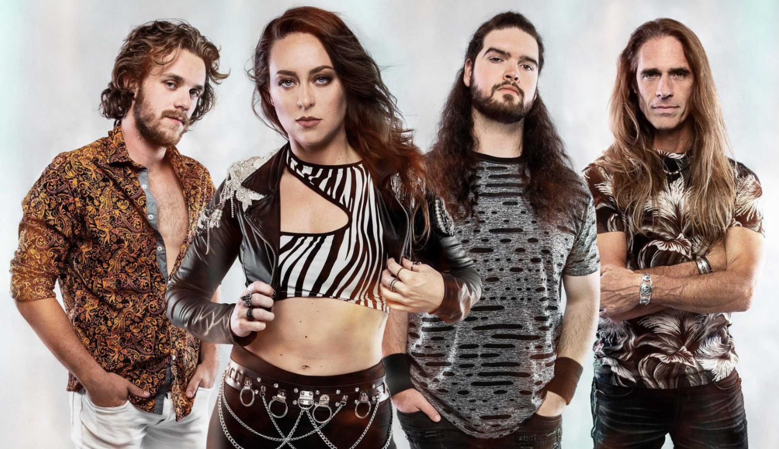A group of four rock band members posing together, with two men and one woman in the foreground and one man slightly behind. They have a rebellious style, with the woman wearing a striped crop top and leather jacket, and the men sporting patterned and distressed shirts.