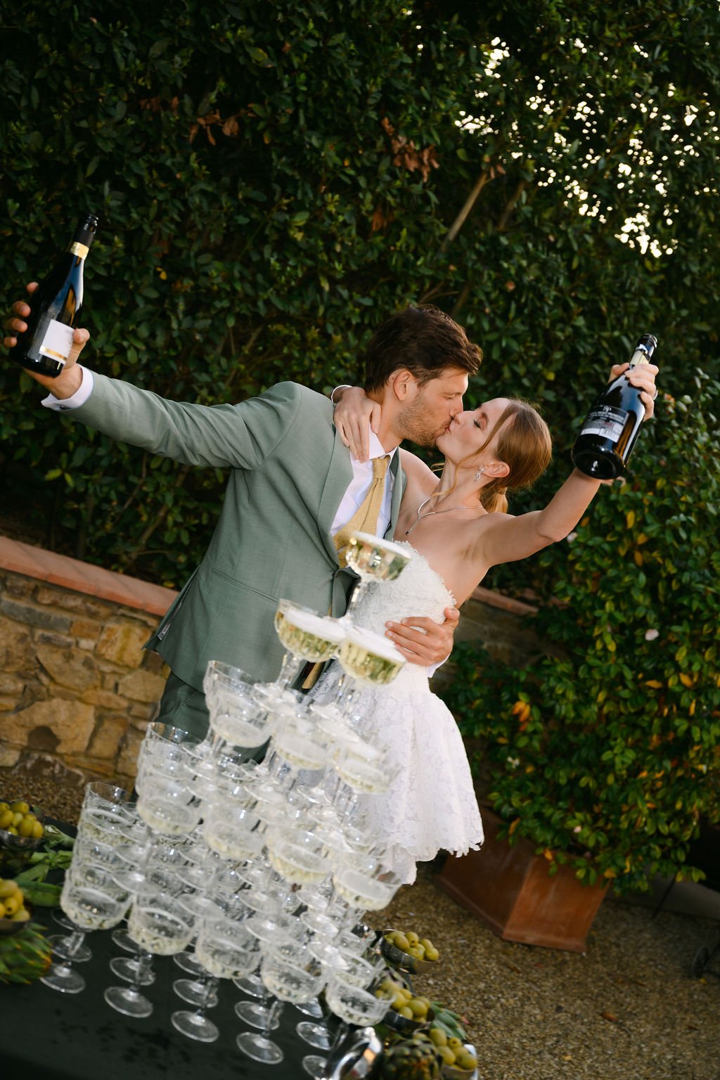 sarapaolucci-bride-and-groom-kissing-in-front-of-champagne-tower.jpg