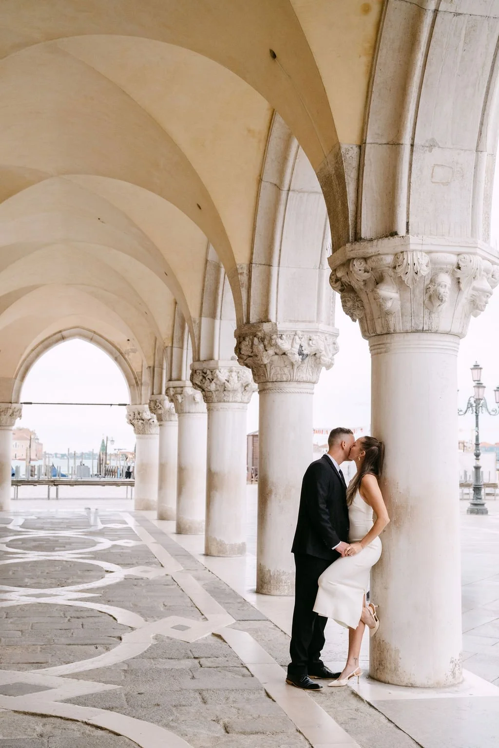 sarapaolucci-groom-kissing-the-bride-against-a-column-in-venice.jpg