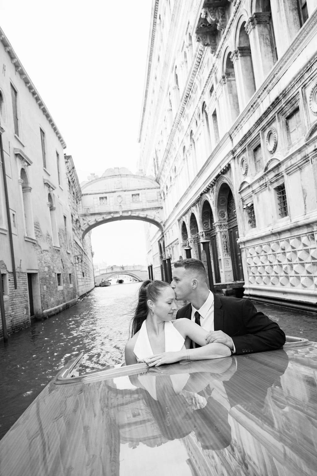 sarapaolucci-groom-kissing-brides-forehead-while-riding-a-boat-in-venice-in-front-of-ponte-dei-sospiri.jpg