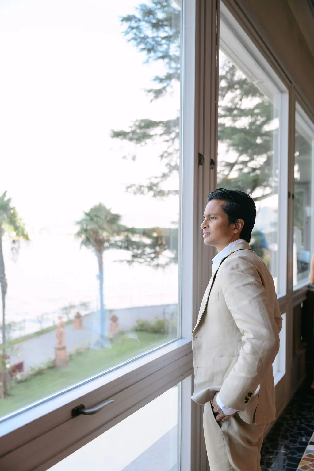 sarapaolucci-groom.looking-outside-the-window-of-villa-flori-hotel.jpg
