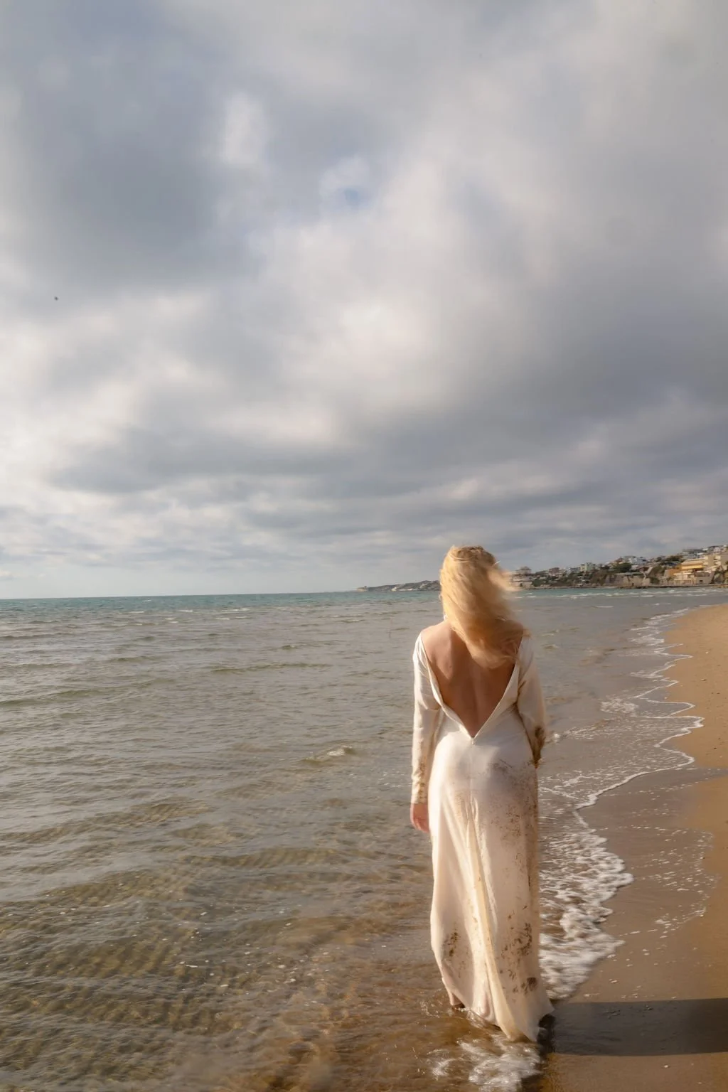 sarapaolucci-bride-portrayed-from-her-back-walking-on-the-beach.jpg