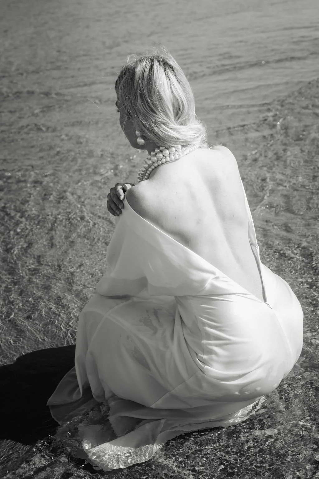 sarapaolucci-bride-sitting-on-the-shoreline.jpg