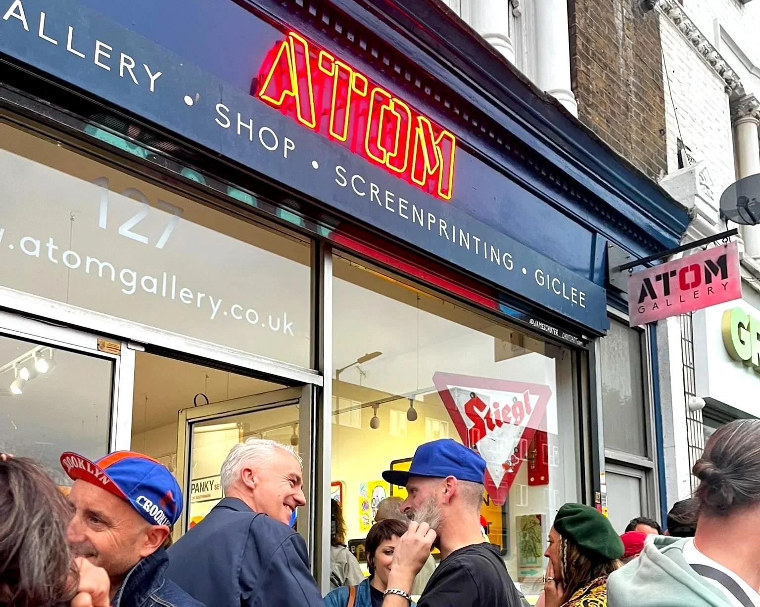 People gathered outside the Atom Gallery, a store that offers art, shop supplies, screen printing, and Giclee printing services.