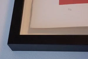 Close-up of a framed picture or document on a wall with a black frame