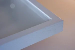 Close-up of a corner of a metallic box or tray with a reflective surface and surrounding edge.