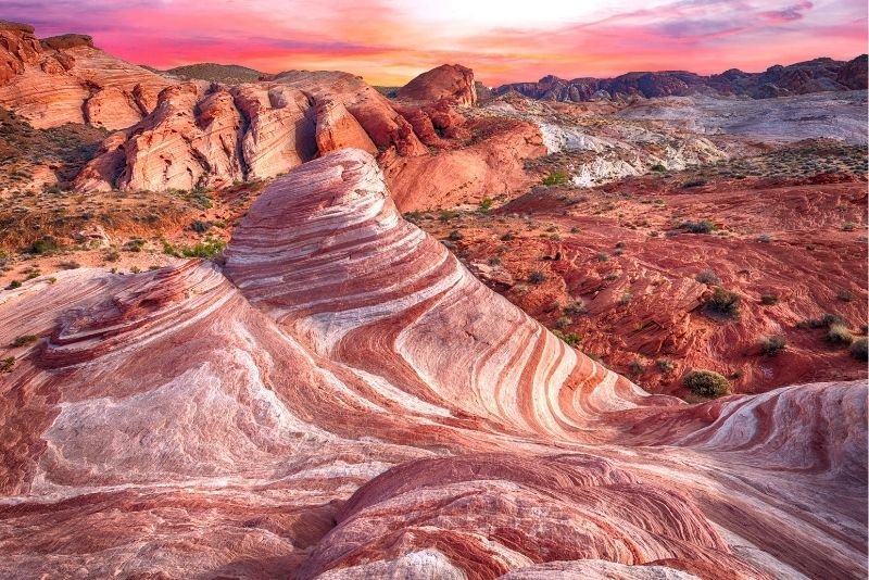 Colorful desert landscape with layered rock formations and a sunset sky.