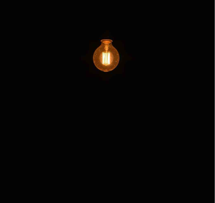 A glowing vintage light bulb hanging in the dark