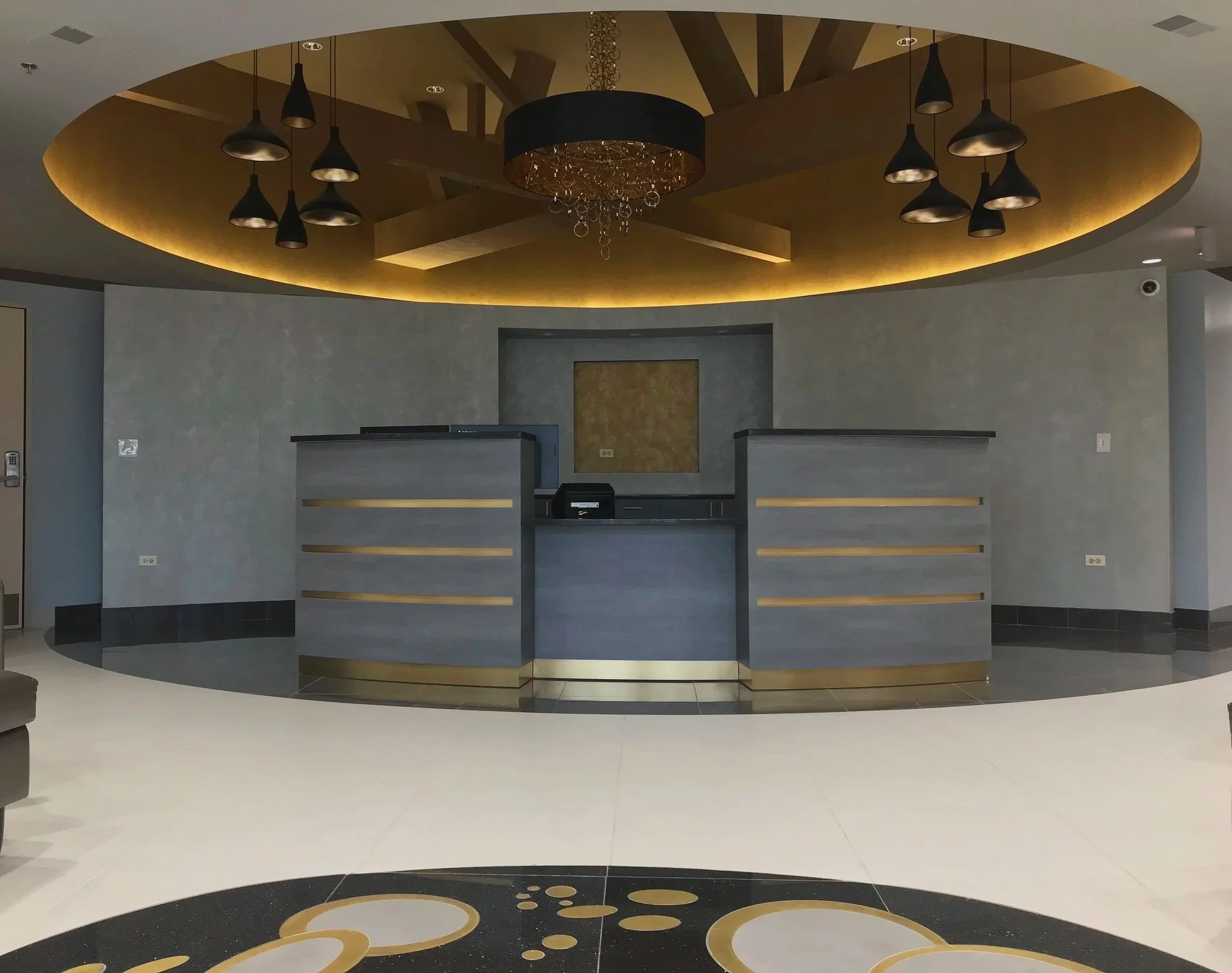 Luxury commercial lobby with circular gold ceiling, chandelier, and custom reception desks