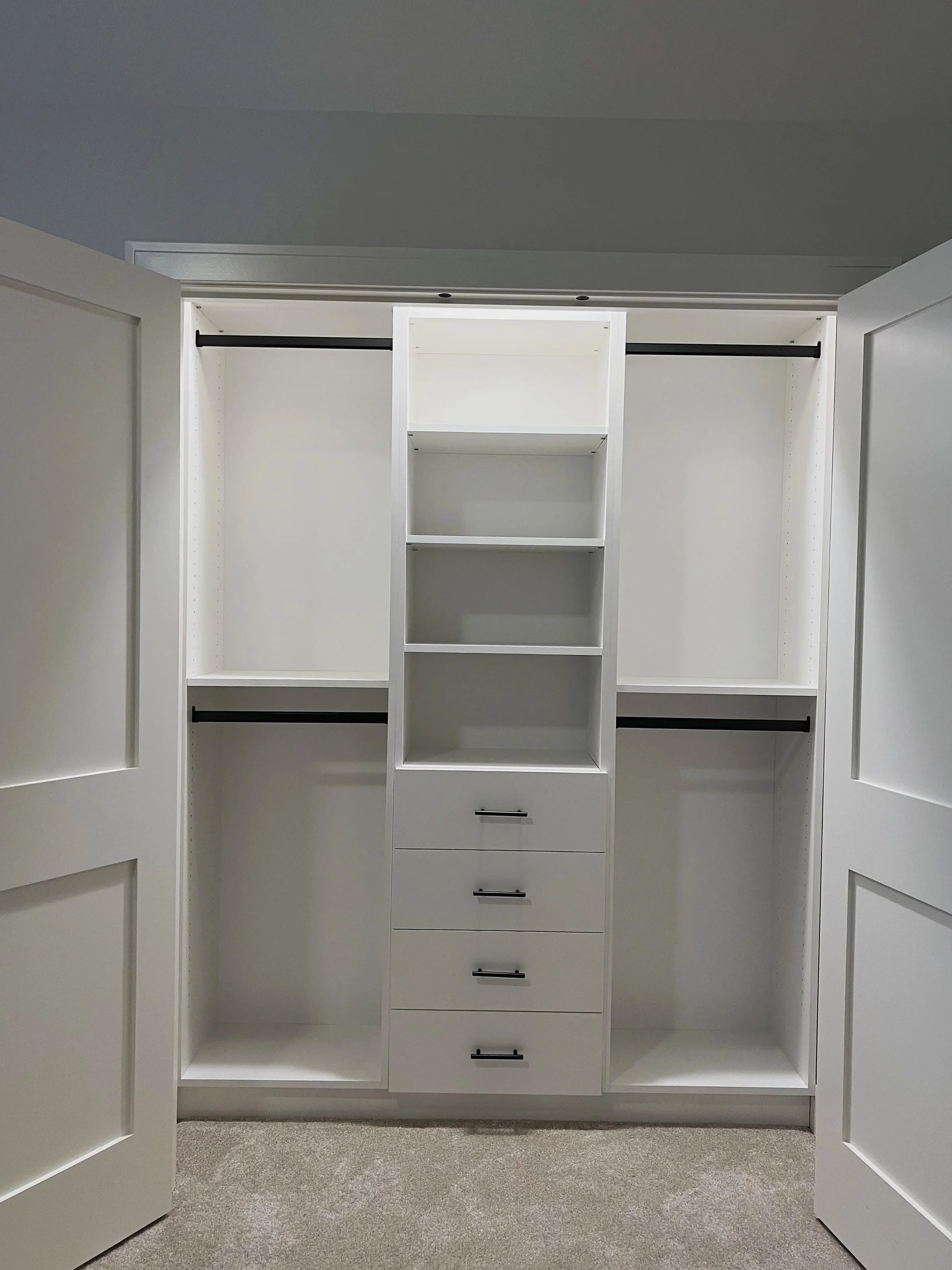 Double-door white reach-in custom closet with hanging rods and drawers