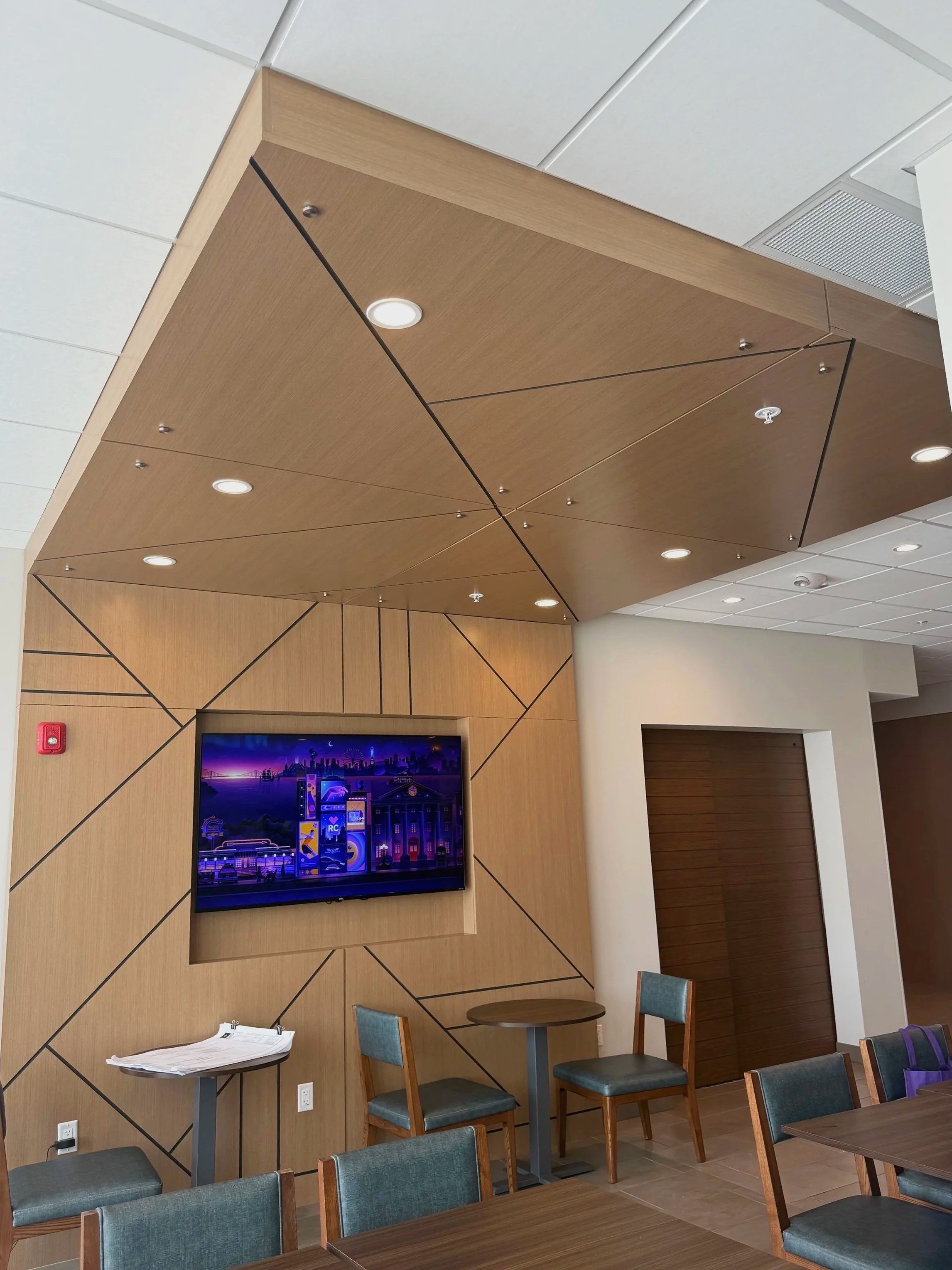 Lounge area with wood-paneled feature wall, mounted TV, and custom seating millwork