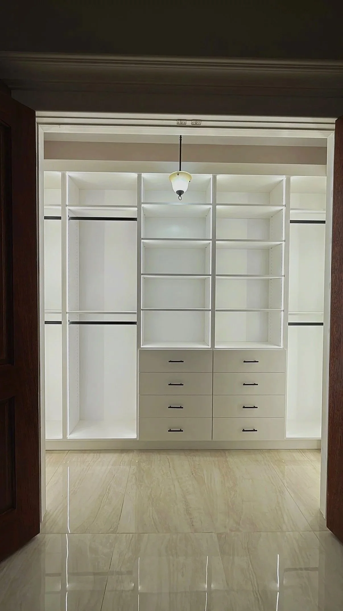White reach-in custom closet with shelves and drawers in tile-floor bedroom