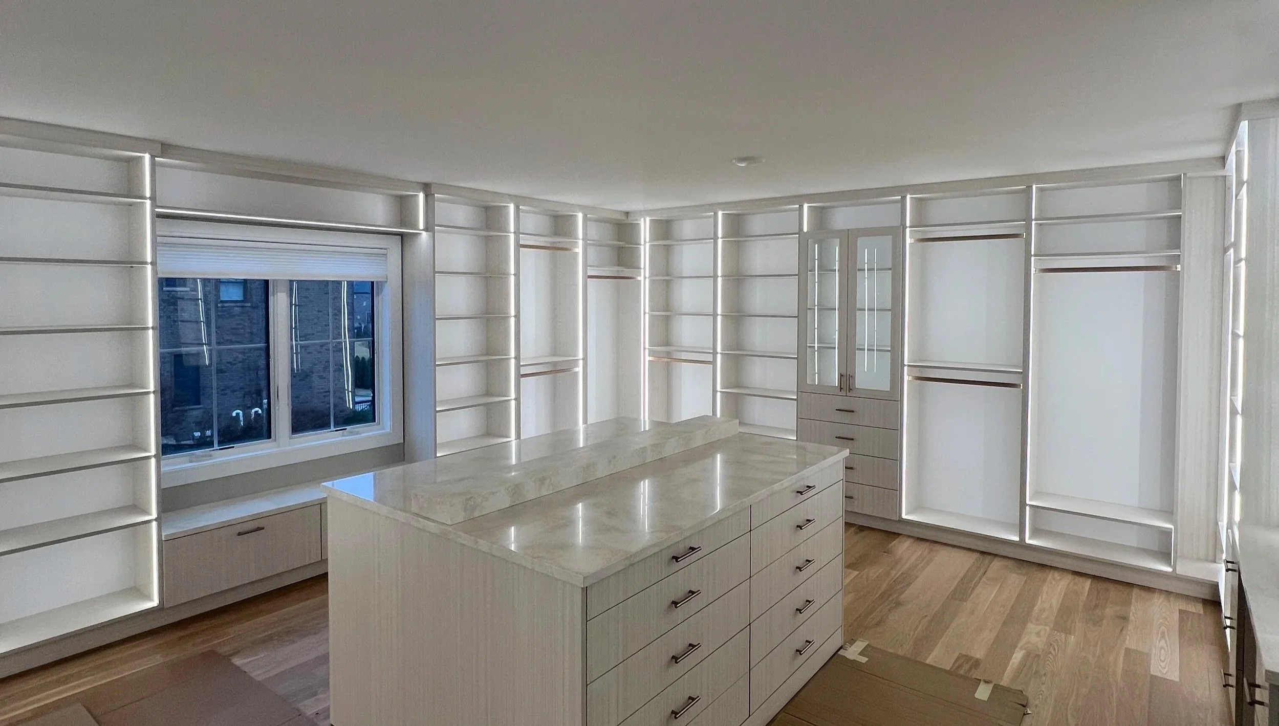 Large white luxury custom walk-in closet with marble-top island and wraparound shelving in Chicago suburbs