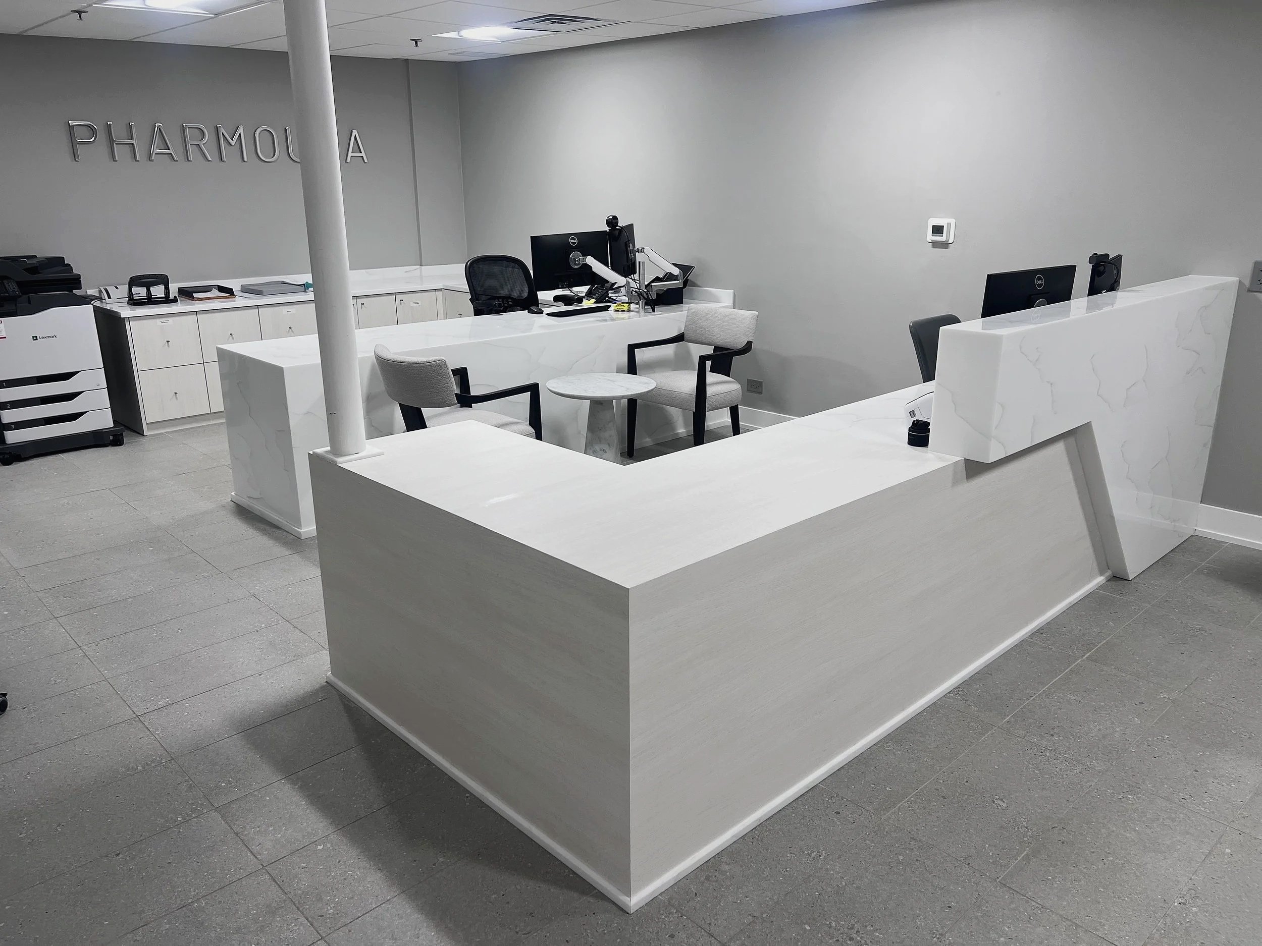 Modern white reception desk in gray office with open workstations