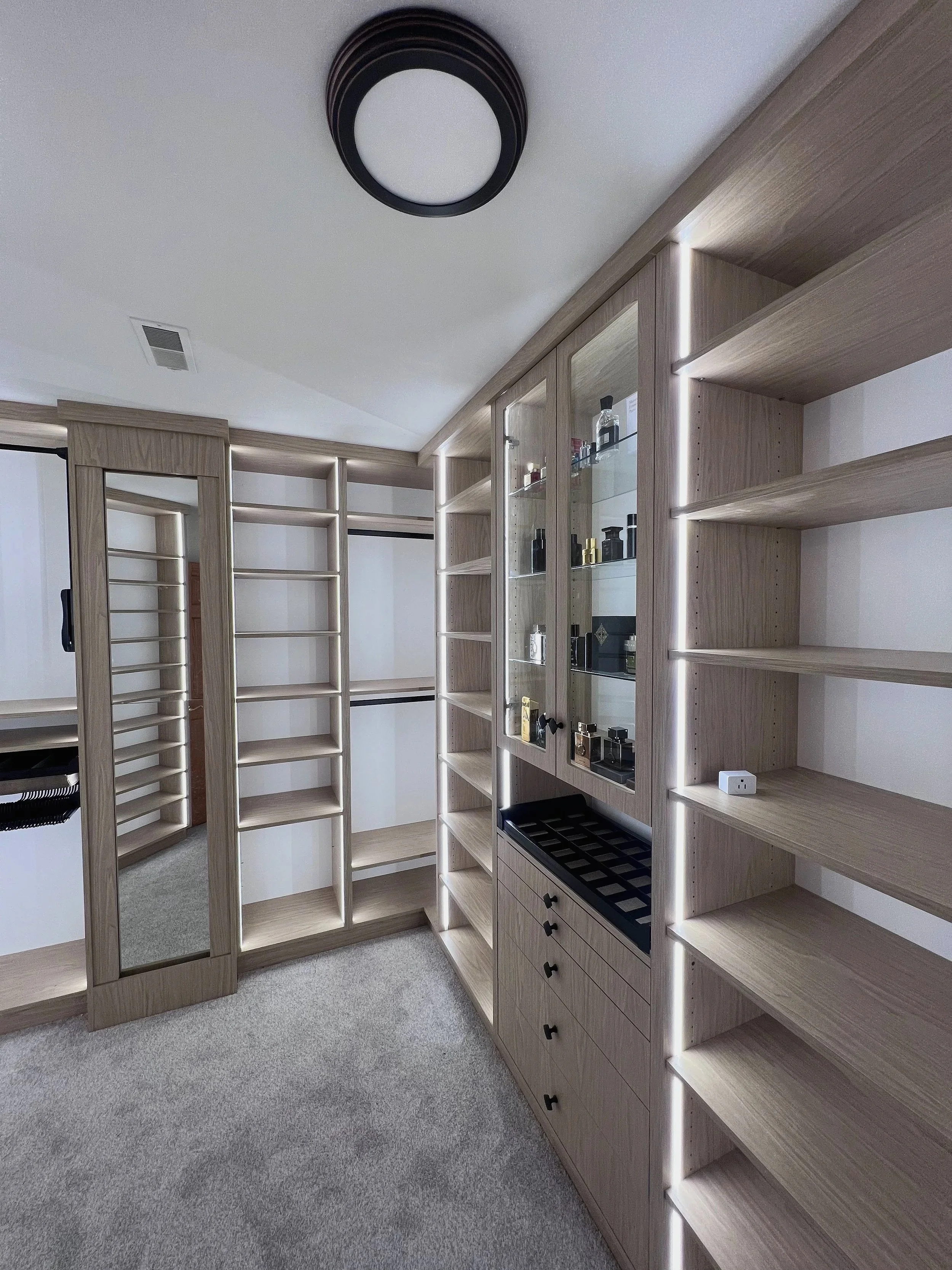 Gray wood custom walk-in closet with built-in mirror, display shelves, and LED accents