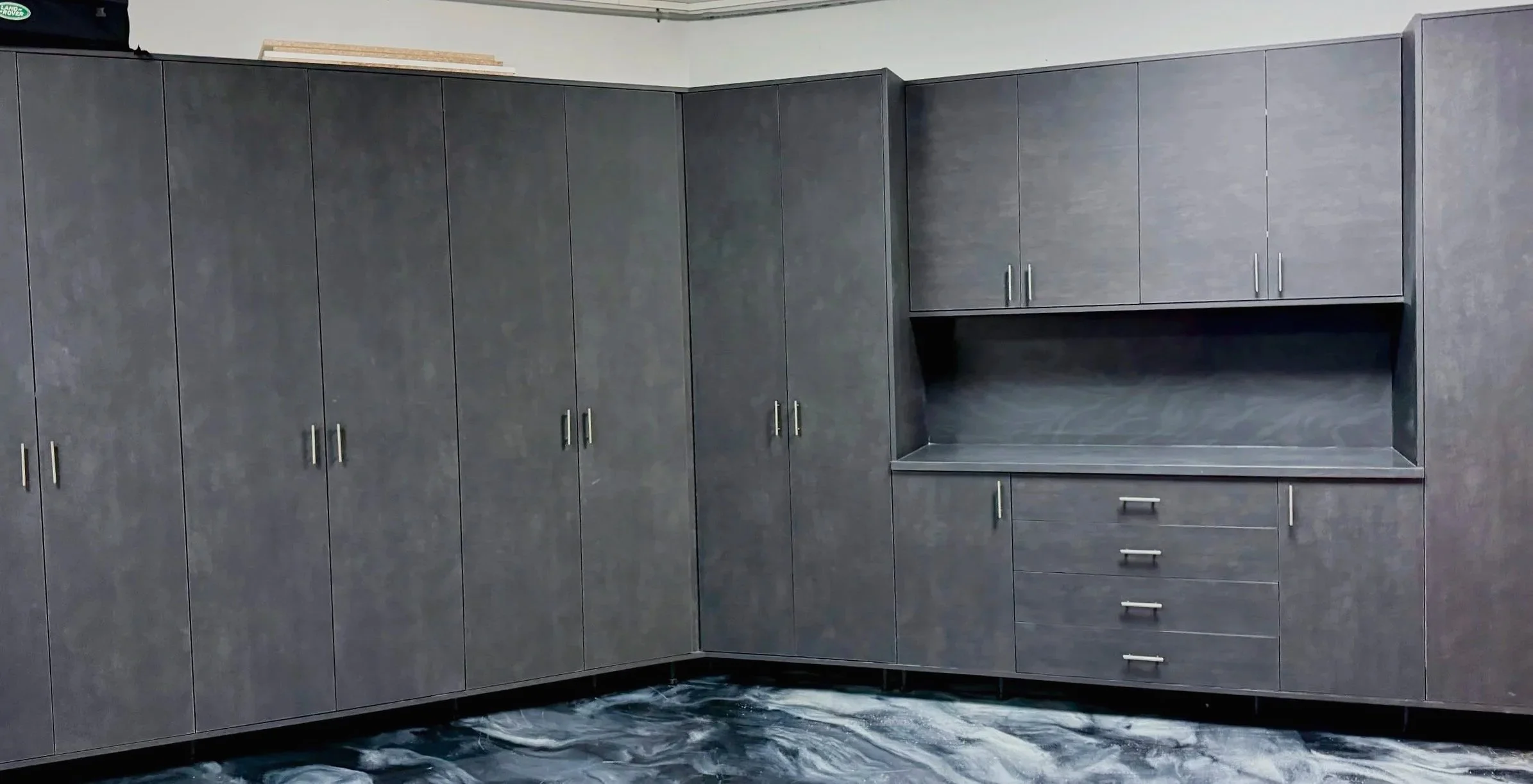 Gray L-shaped garage cabinet system with drawers and open work area