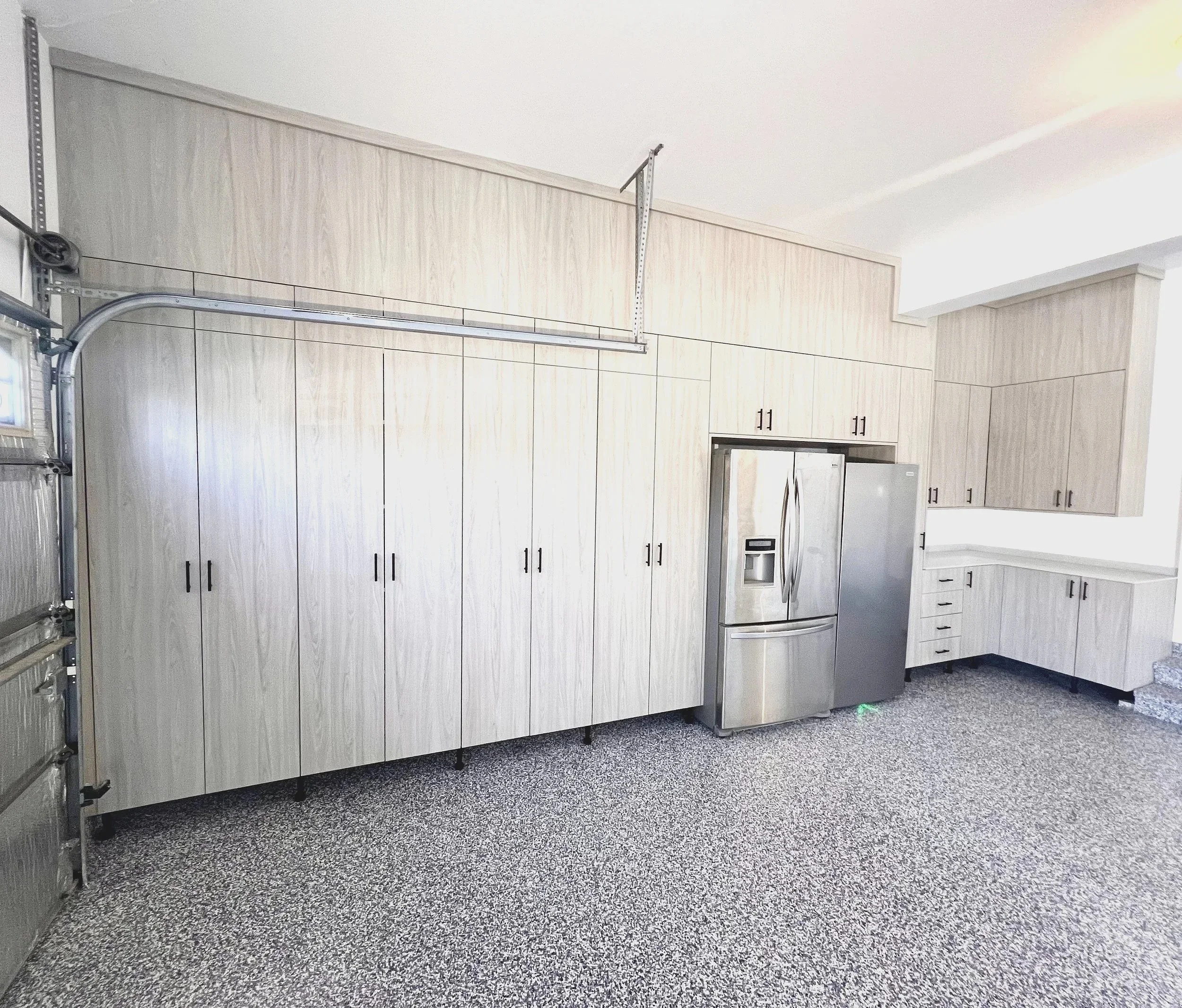 Light wood garage storage cabinets with integrated fridge and workbench