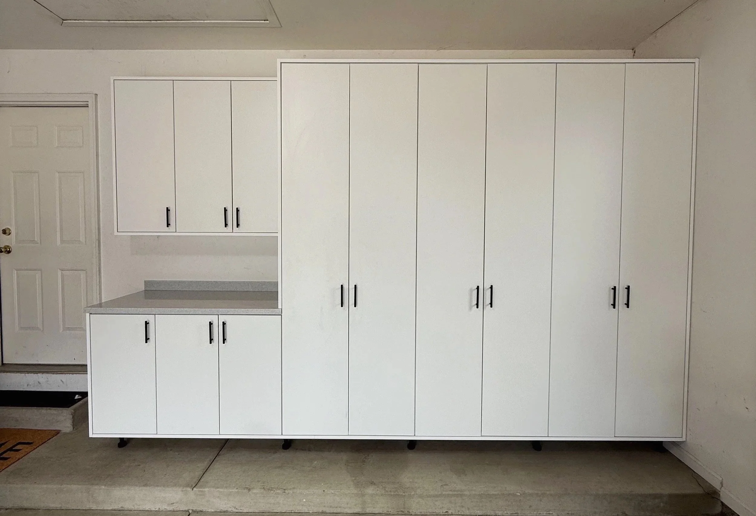 White garage storage cabinets with built-in counter and upper cupboards