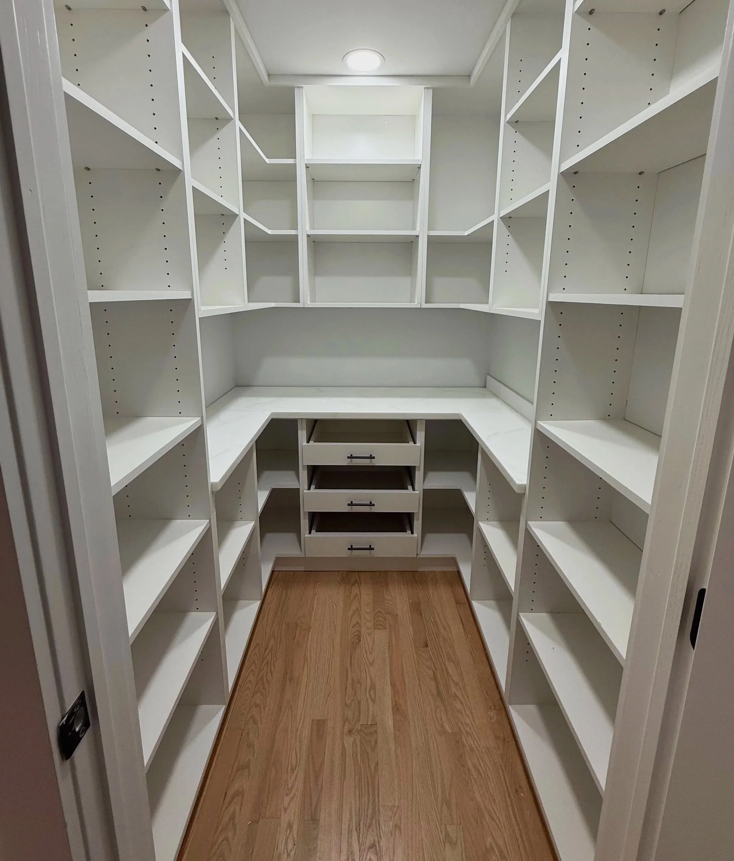 U-shaped white pantry shelving with drawers and wood floor