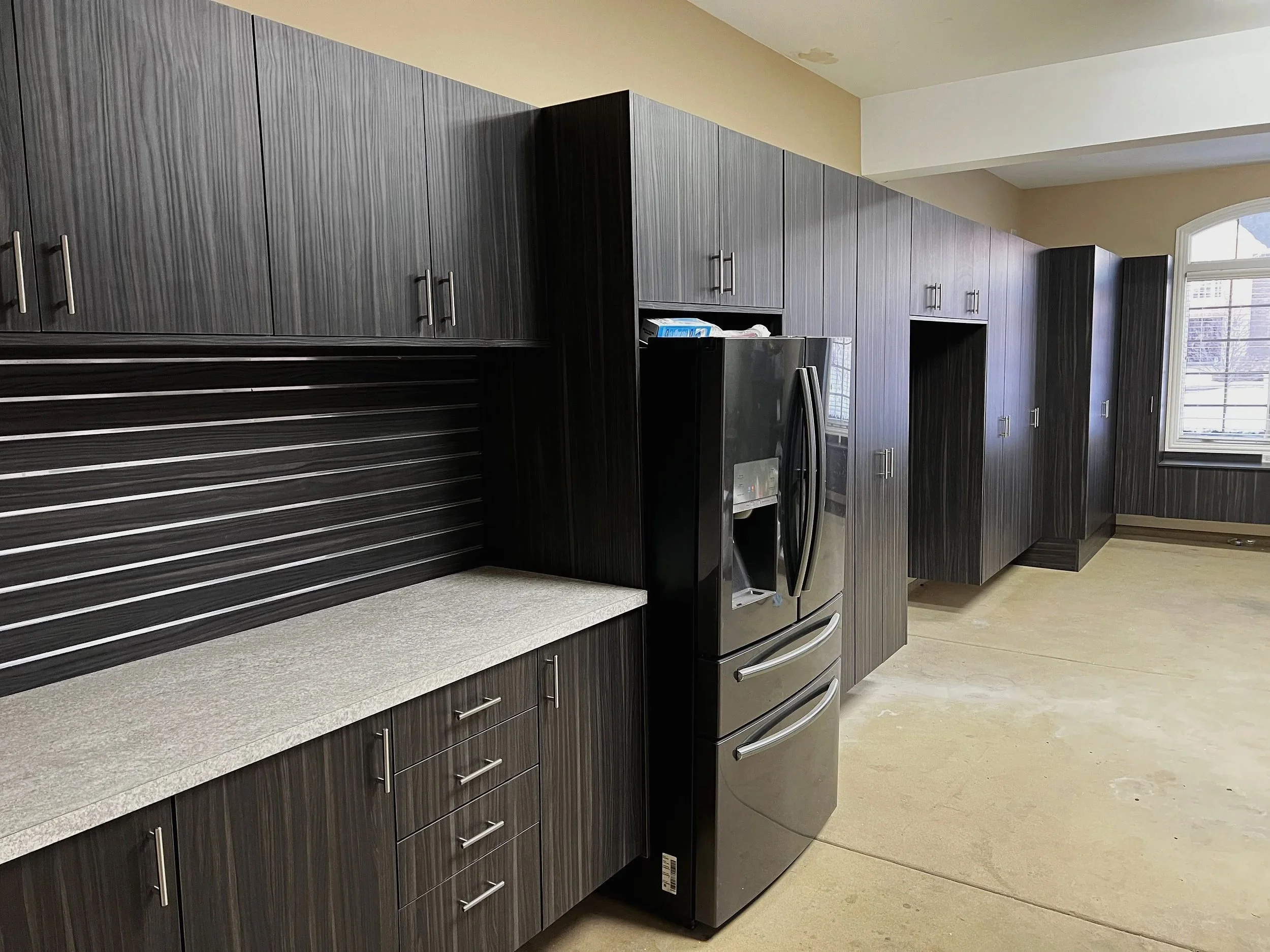 Dark gray garage cabinets with slatwall tool storage and long countertop