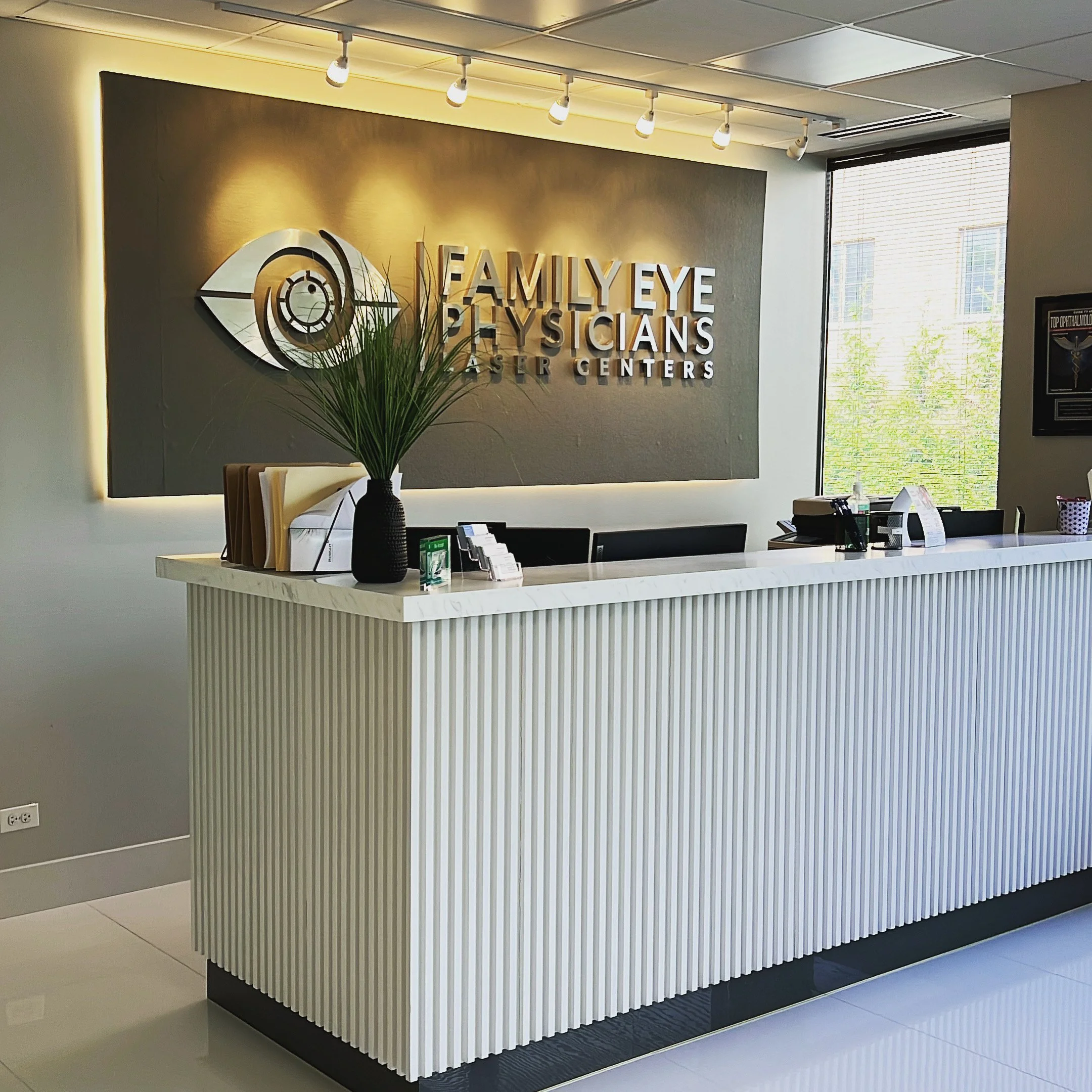 Family Eye Physicians reception desk with fluted front and branded wall sign