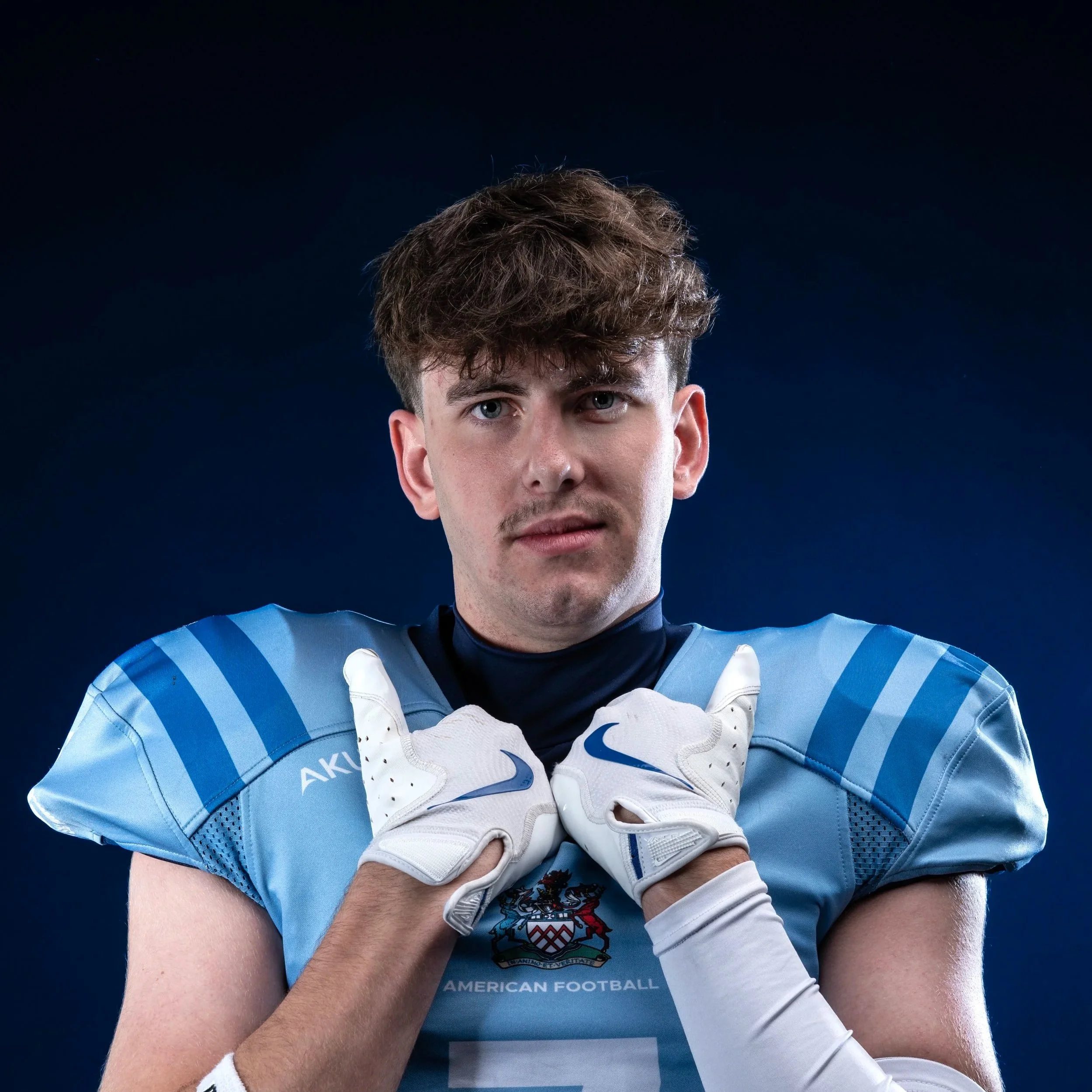 A football player wearing a blue helmet and jersey with 'TEAM GLOBS' written on the sleeve, holding a football, standing in front of a blue background with 'Glads' in white text and a logo at the top.