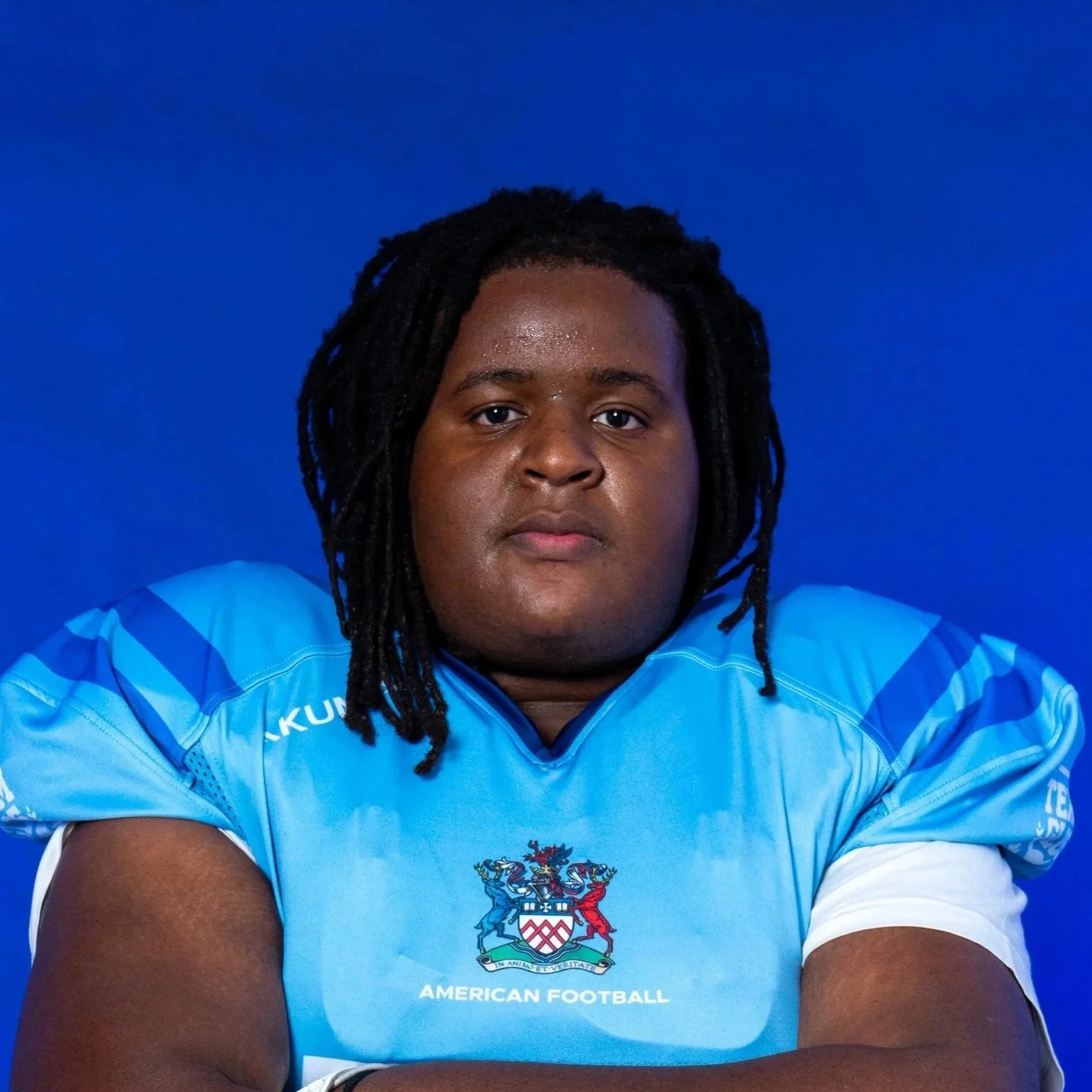 Young male football player in blue uniform and silver helmet facing forward.