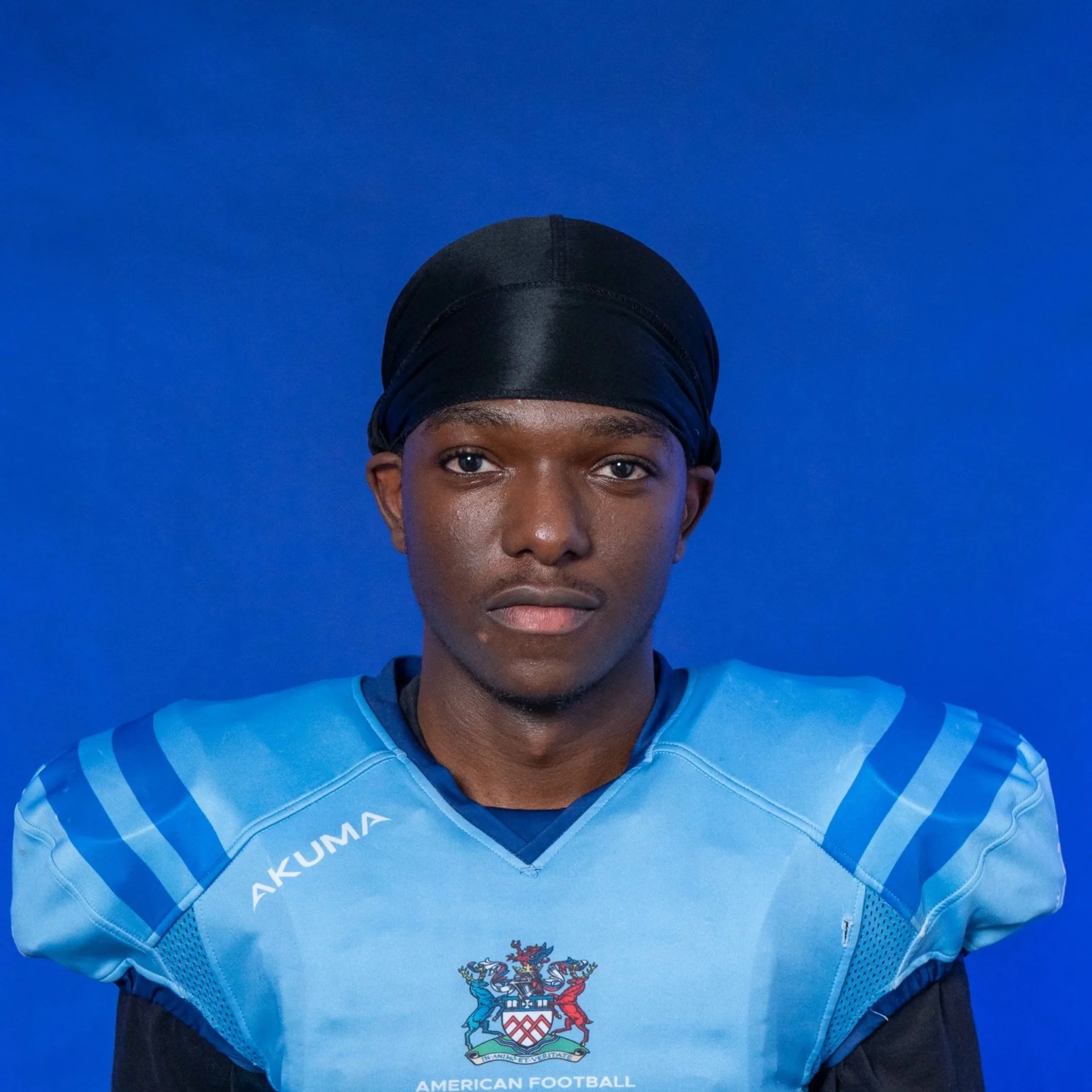An American football player wearing a blue helmet and jersey holding a football, standing in front of a blue background with 'Glads' and the Michigan State Spartans logo.