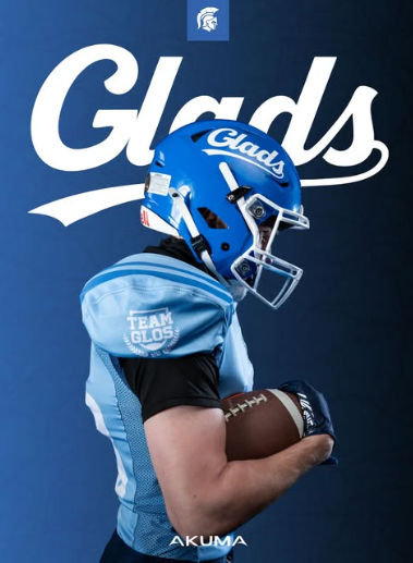 Young football player wearing a blue helmet and jersey, holding a football against a blue backdrop with 'Glads' and the Michigan State Spartans logo.