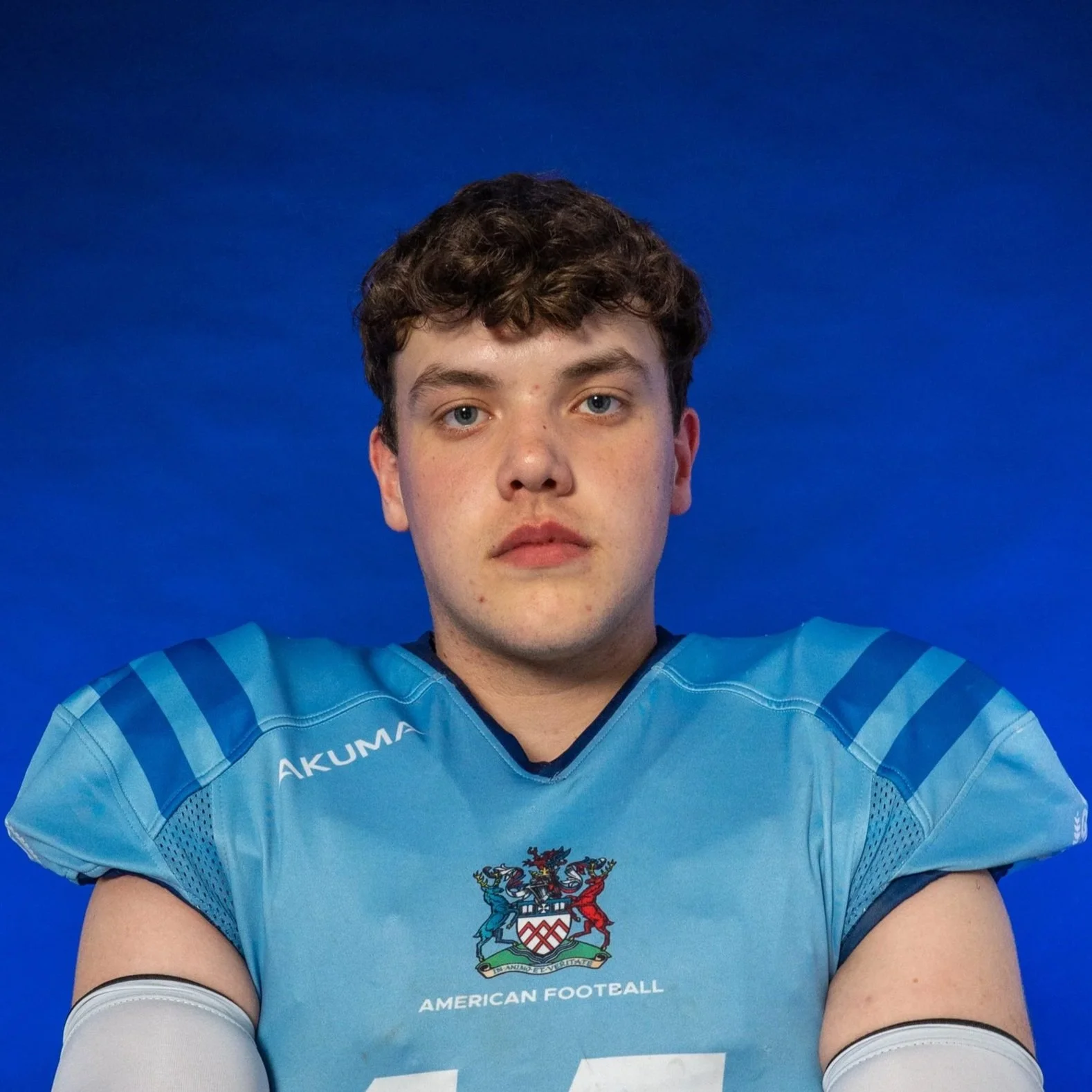 A football player wearing a white Riddell helmet, a light blue jersey with the number 14, and black gloves against a black background.