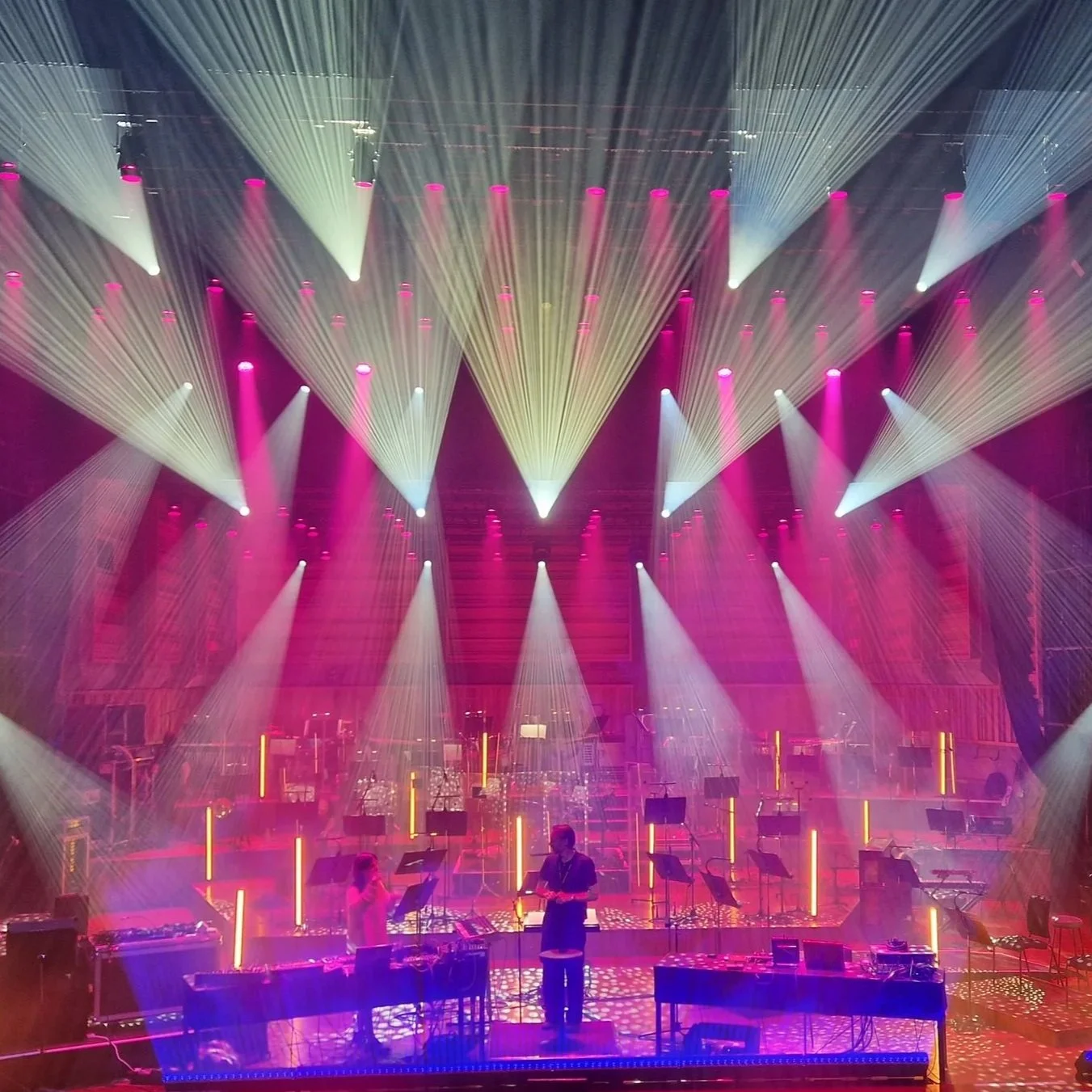 Colorful stage setup with vibrant lighting, fog, and multiple musical instruments arranged for a concert or performance.