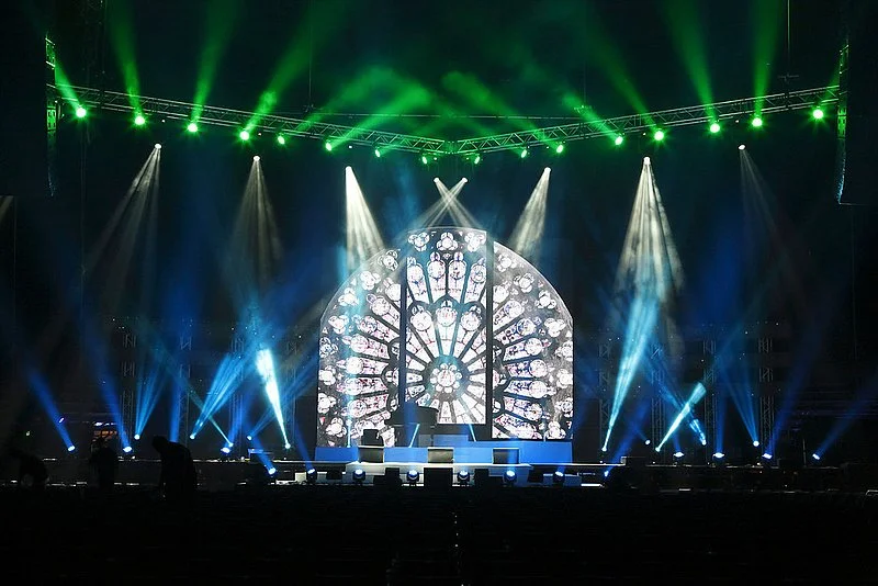 Stage with colorful lighting and a large circular screen displaying stained glass window patterns.