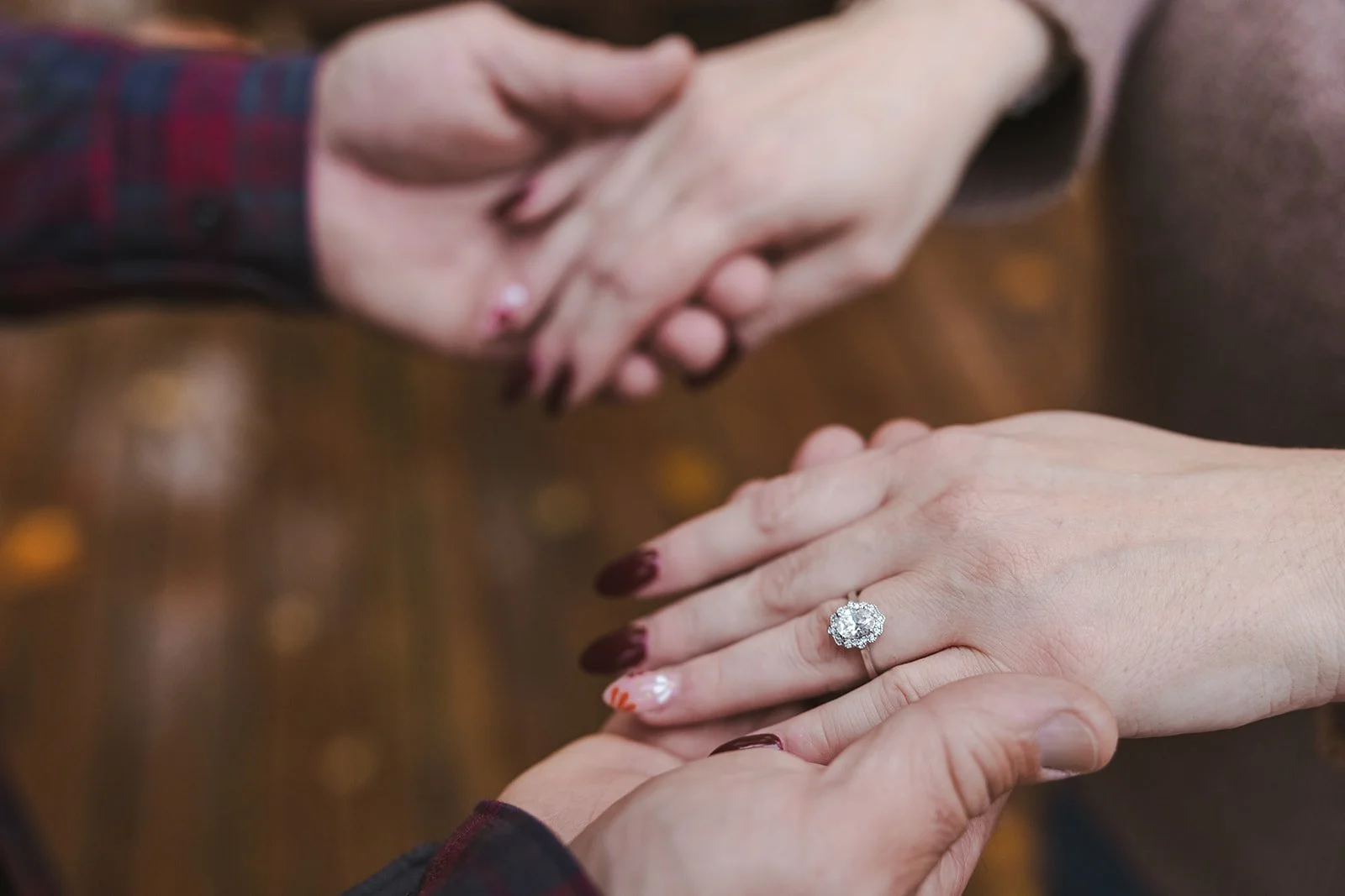Couple holding hands with engagement ring  Cabin Propsal  Fedora Media.jpg
