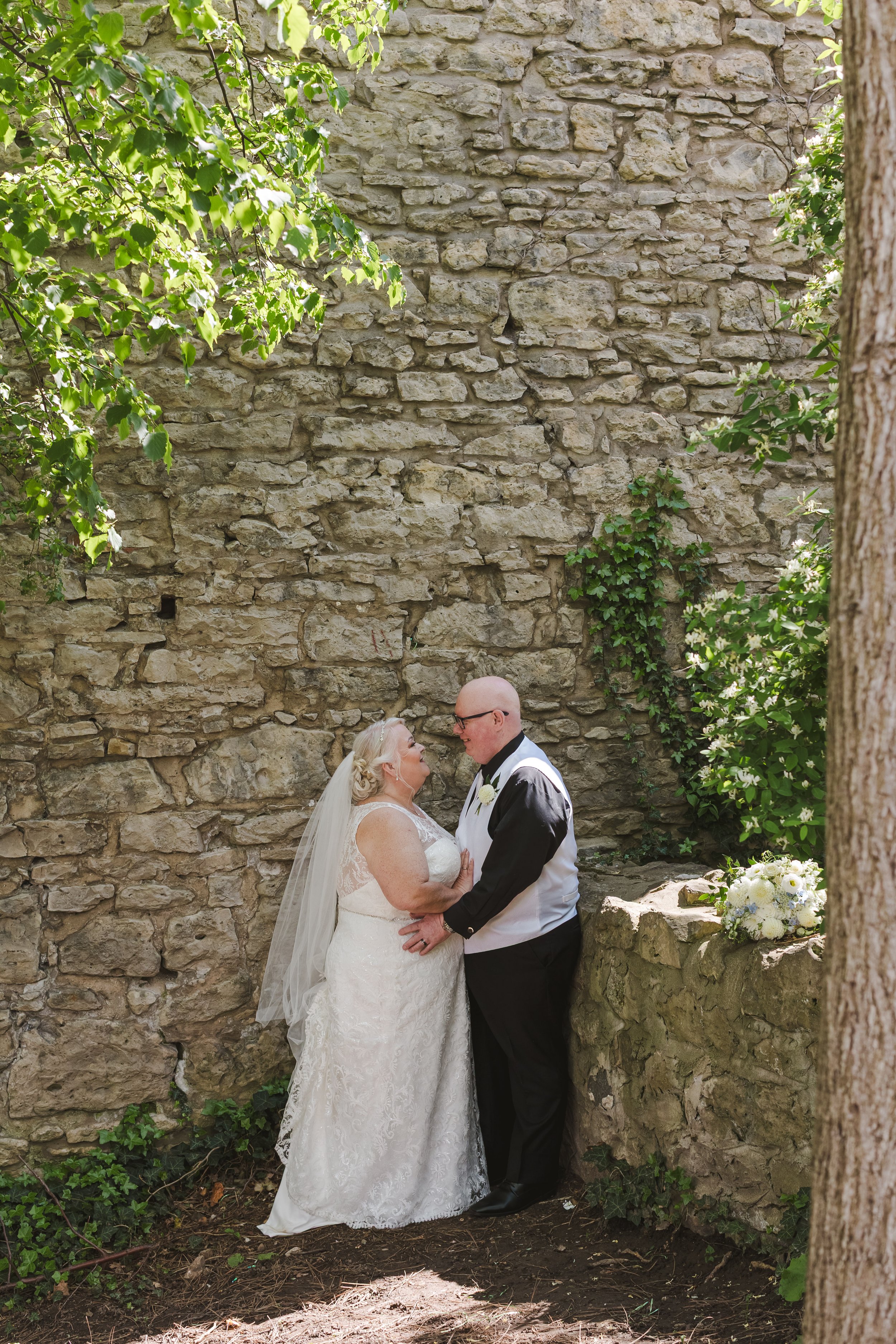 bride-and-groom-in-front-of-brick-wall-fedora-media.jpg