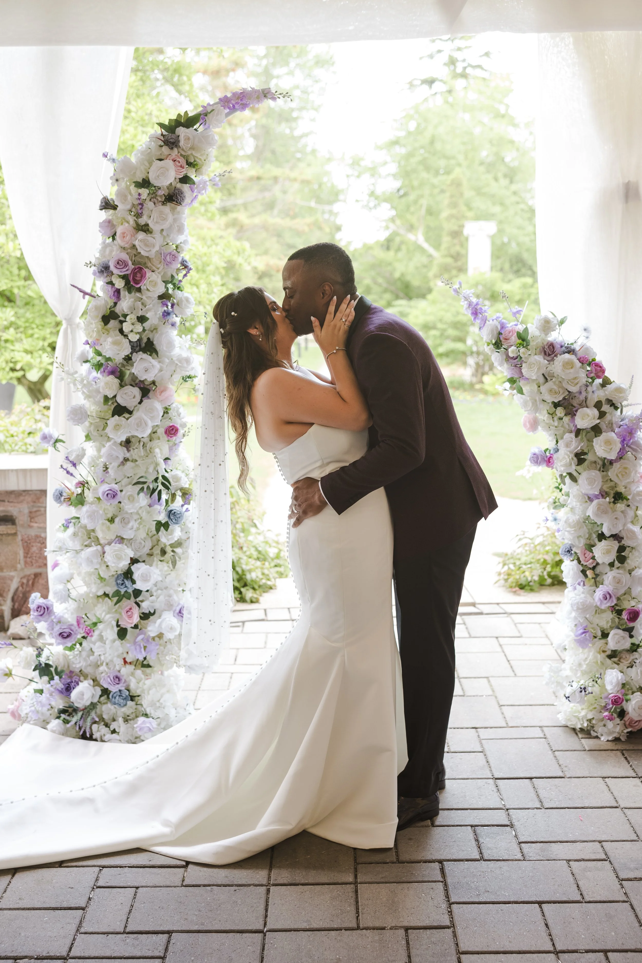 couple-embrace-under-flower-arch-fedora-media.jpg