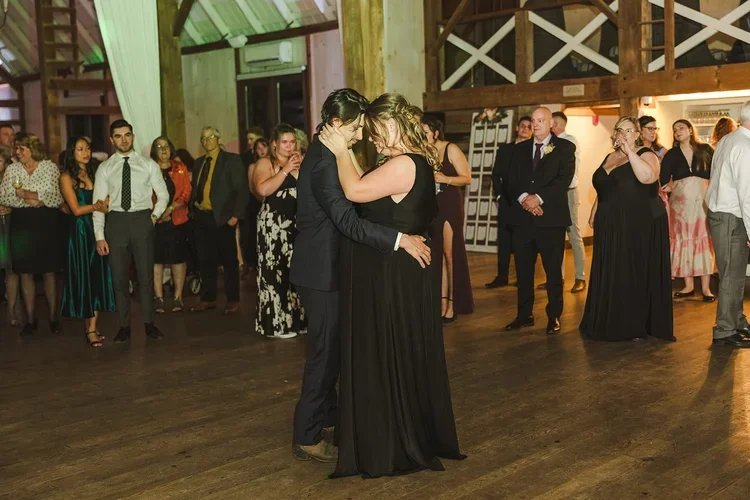 Wedding+party+in+black+dress+and+suite+dance+in+barn+photo+by+Fedora+Media.webp