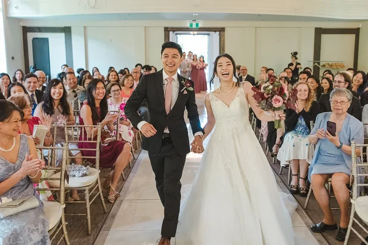 Bride+and+Groom+in+pink+tie+dance+down+the+aisle+photo+by+Fedora+Media.webp