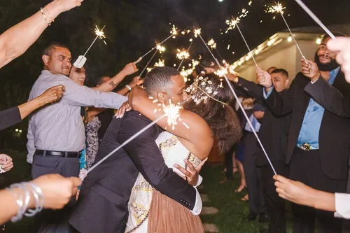 Bride+and+groom+kiss+under+sparklers+photo+by+Fedora+Media.webp
