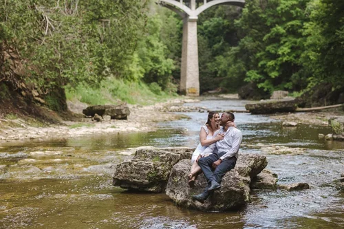 Couple+kiss+at+engagement+photoshoot+at+Elora+Gorge+bridge+photo+by+Fedora+Media.webp