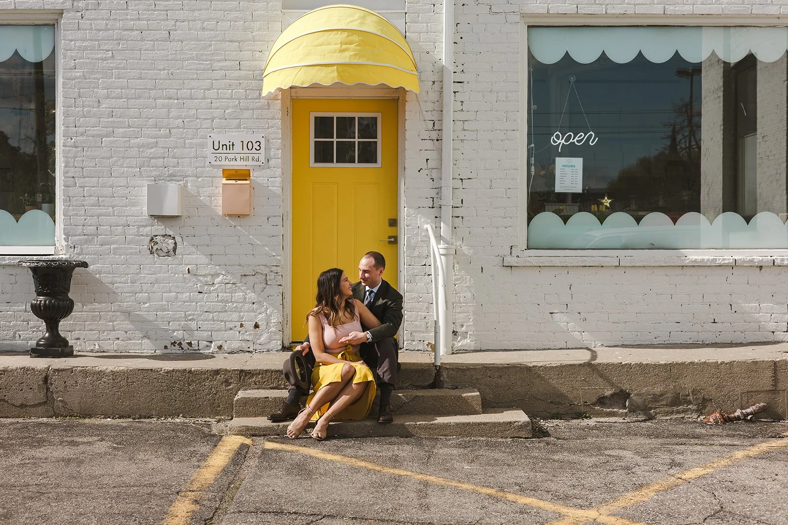 Couple sitting on steps in front of yellow door  Ontario Engagement  Fedora Media.jpg