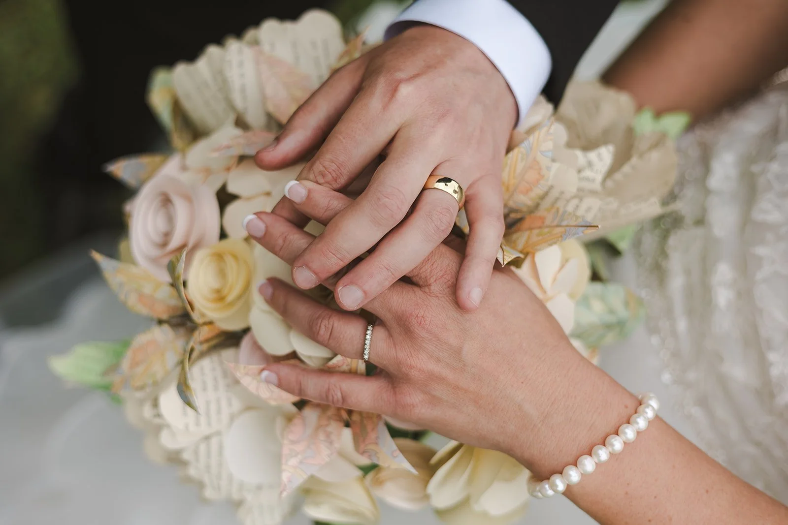 Bride and groom holding hands showcasing rings over bouquet  Hamilton, ON  Glen Drummond Farm  Fedora Media.jpg