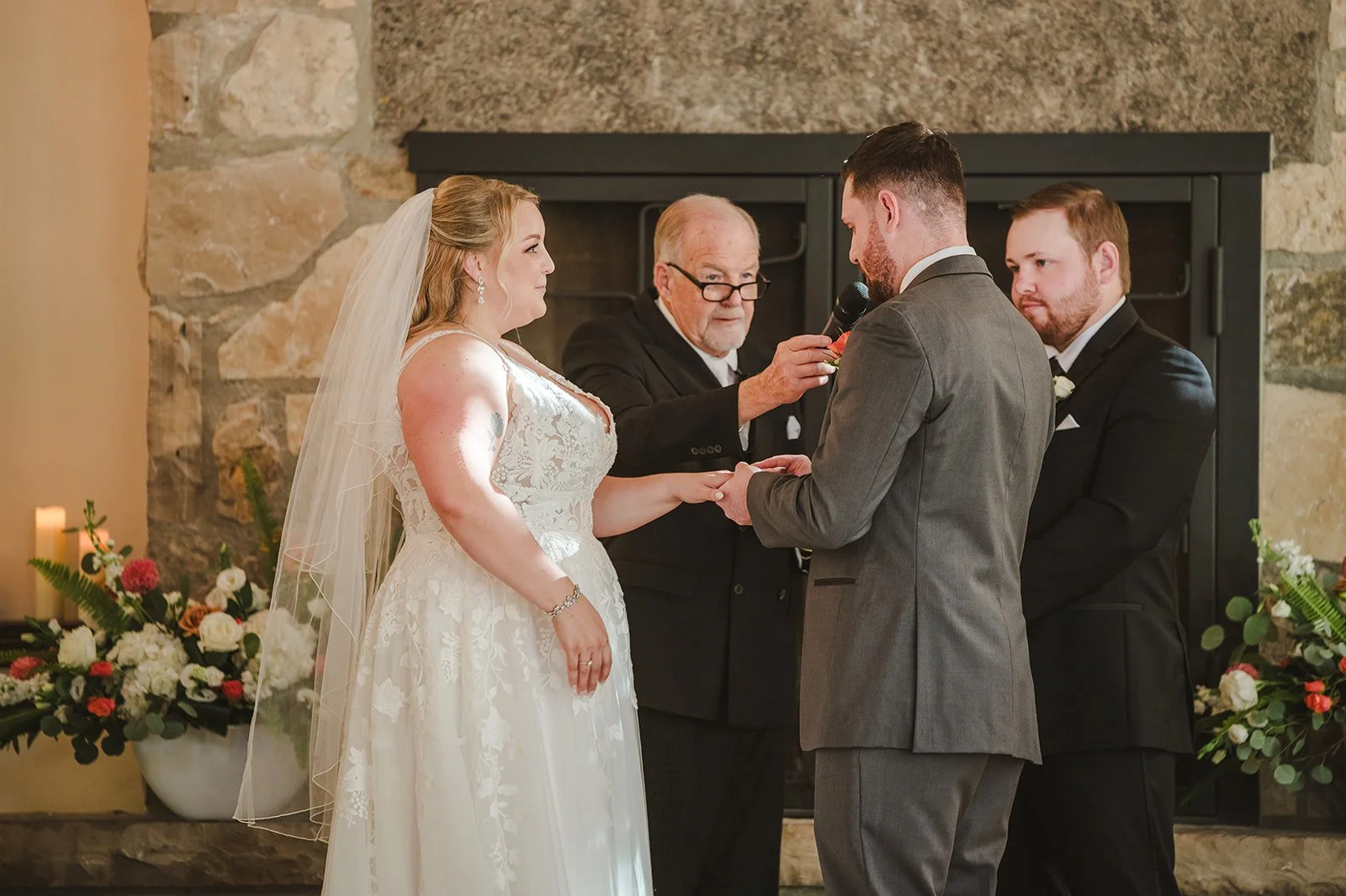 Groom puts wedding band on bride's finger during wedding ceremony  Ancaster,  ON  Ancaster Mill  Fedora Media.jpg