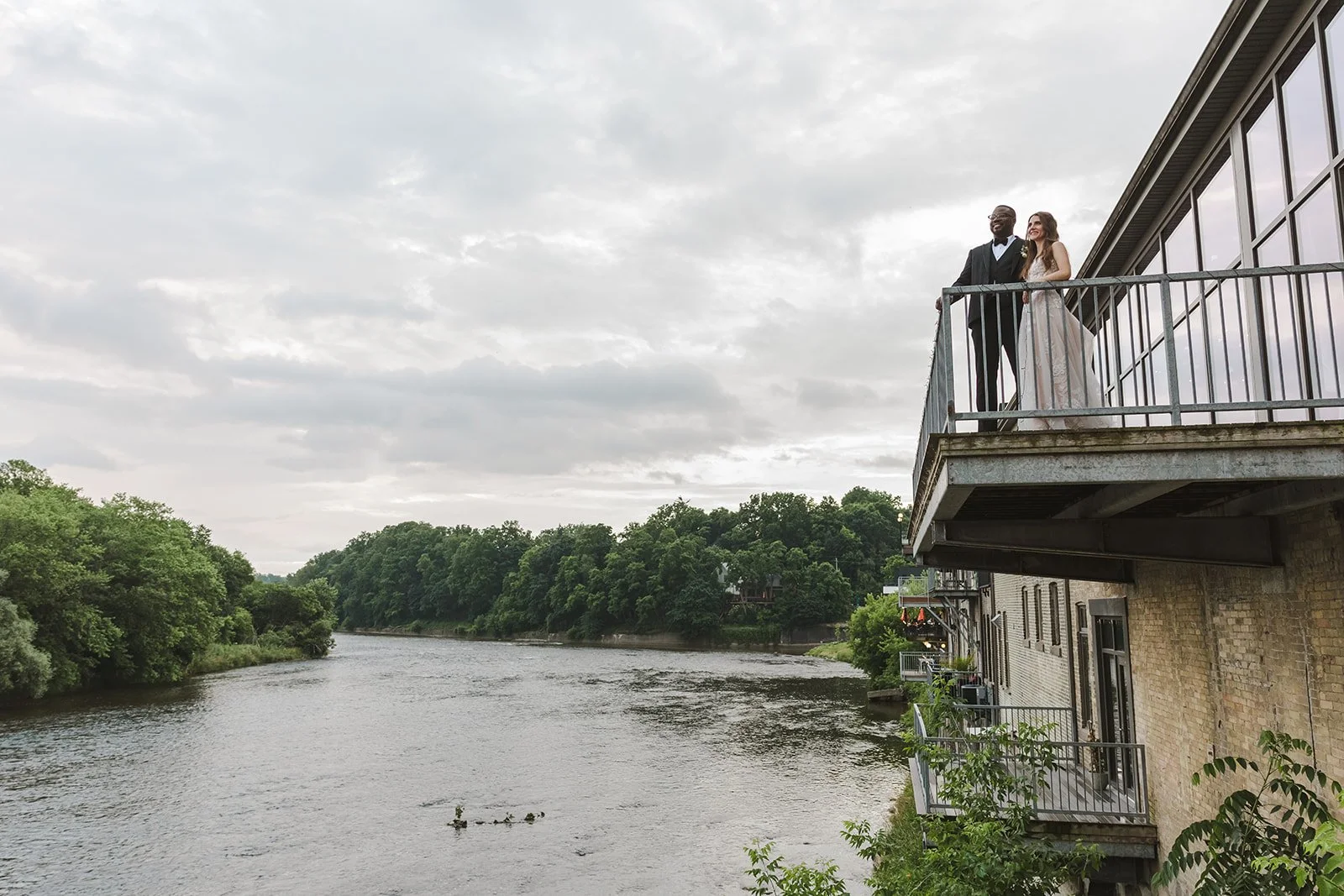 Bride and groom on balcony overlooking river  River's Edge  Arlington Hotel  Paris, ON  Fedora Media.jpg