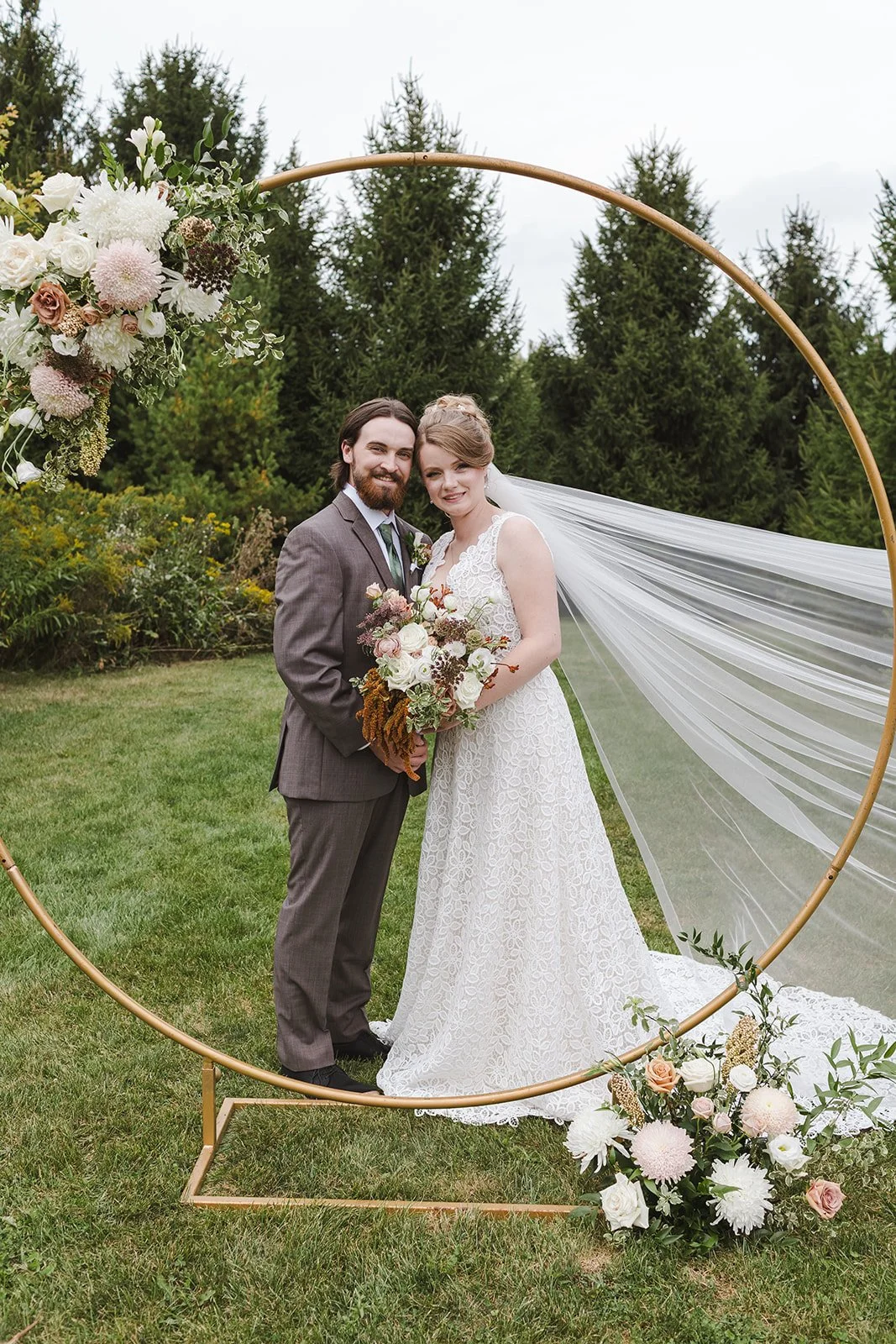 Bride and groom smiling behind hoop arch  Cloudnine Alpaca Farm  Fedora Media.jpg