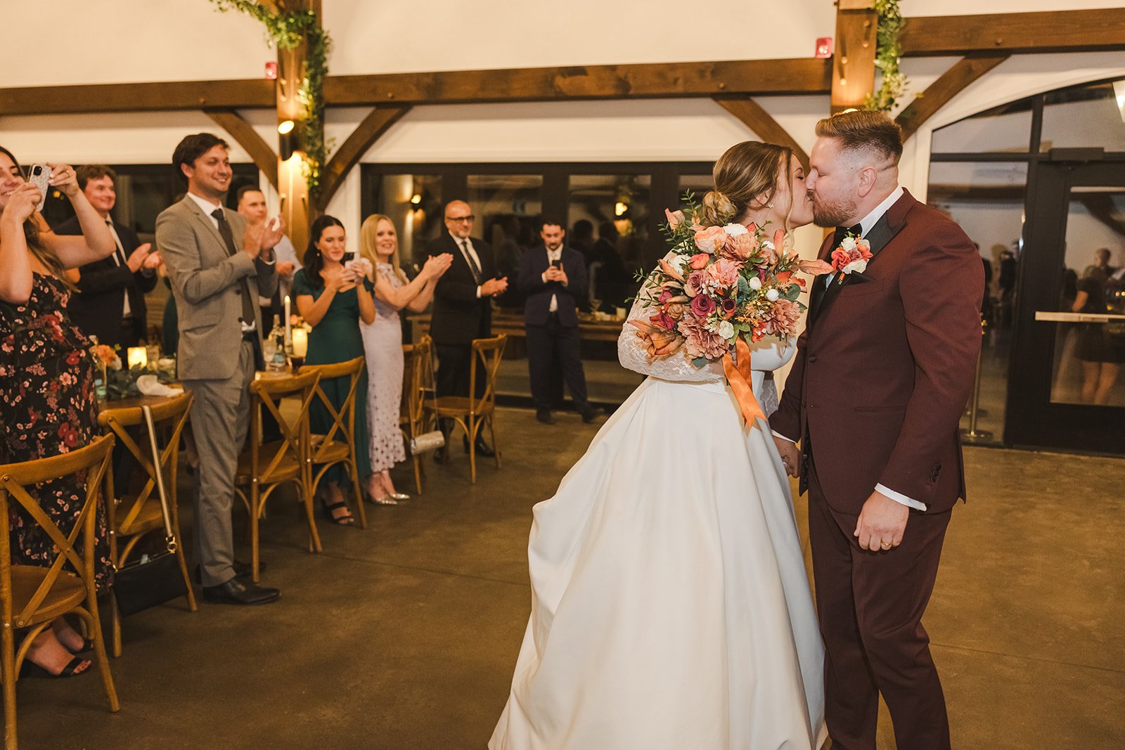 Bride holding bouquet kissing groom guests clapping  Erin Estates  Fedora Media.jpg