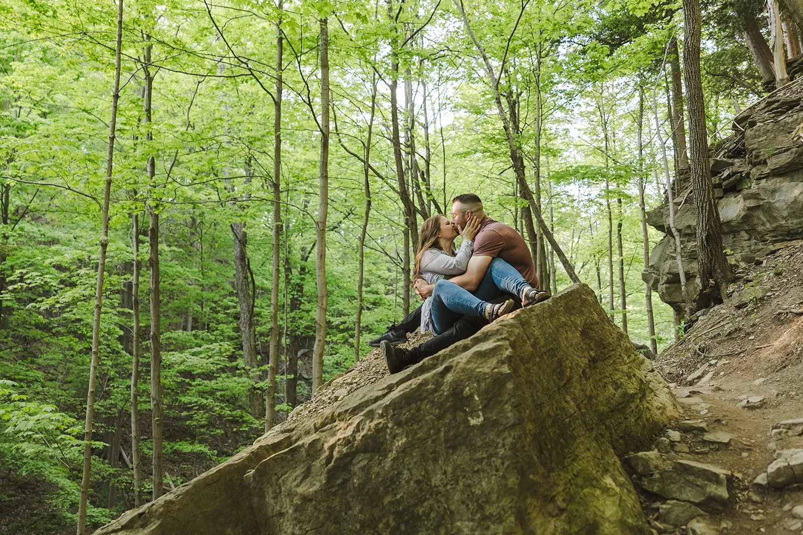 Couple sitting on rock kissing in forest  Ontario Engagement  Fedora Media.jpg
