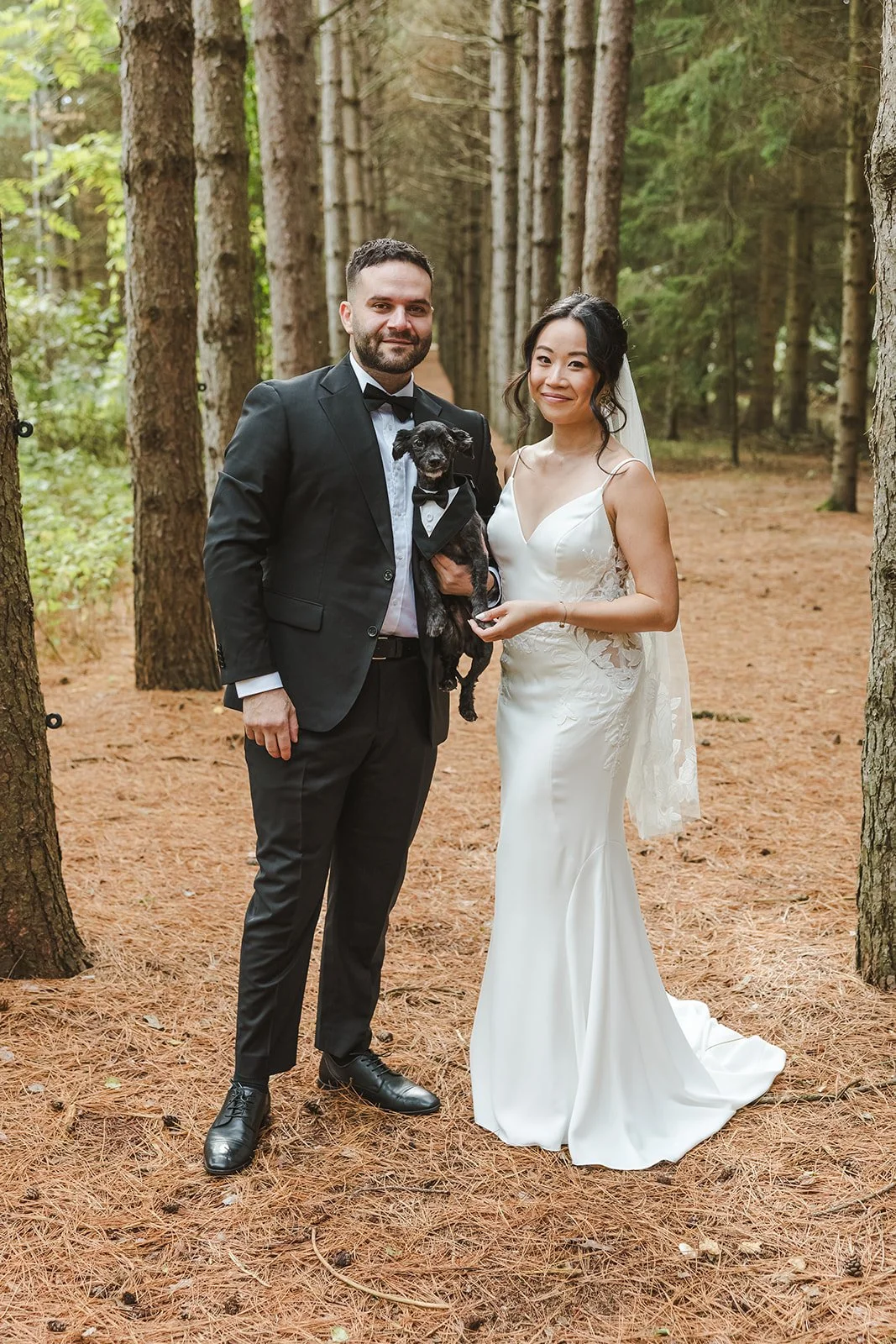 Bride and groom posing with puppy in forest  Erin Estates  Fedora Media.jpg