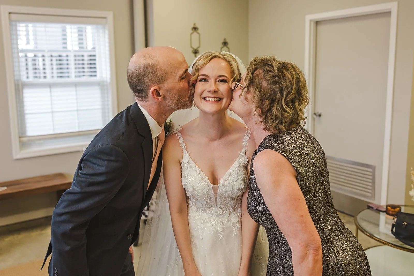 Mom and Dad kiss Bride on her cheeks  Four Fathers  Cambridge, ON  Fedora Media.jpg