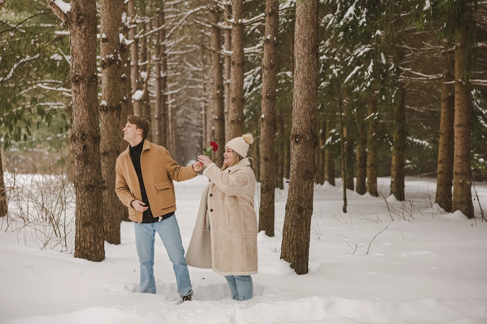 Man giving woman rose in snowy forest  Ontario Engagement  Fedora Media .jpg