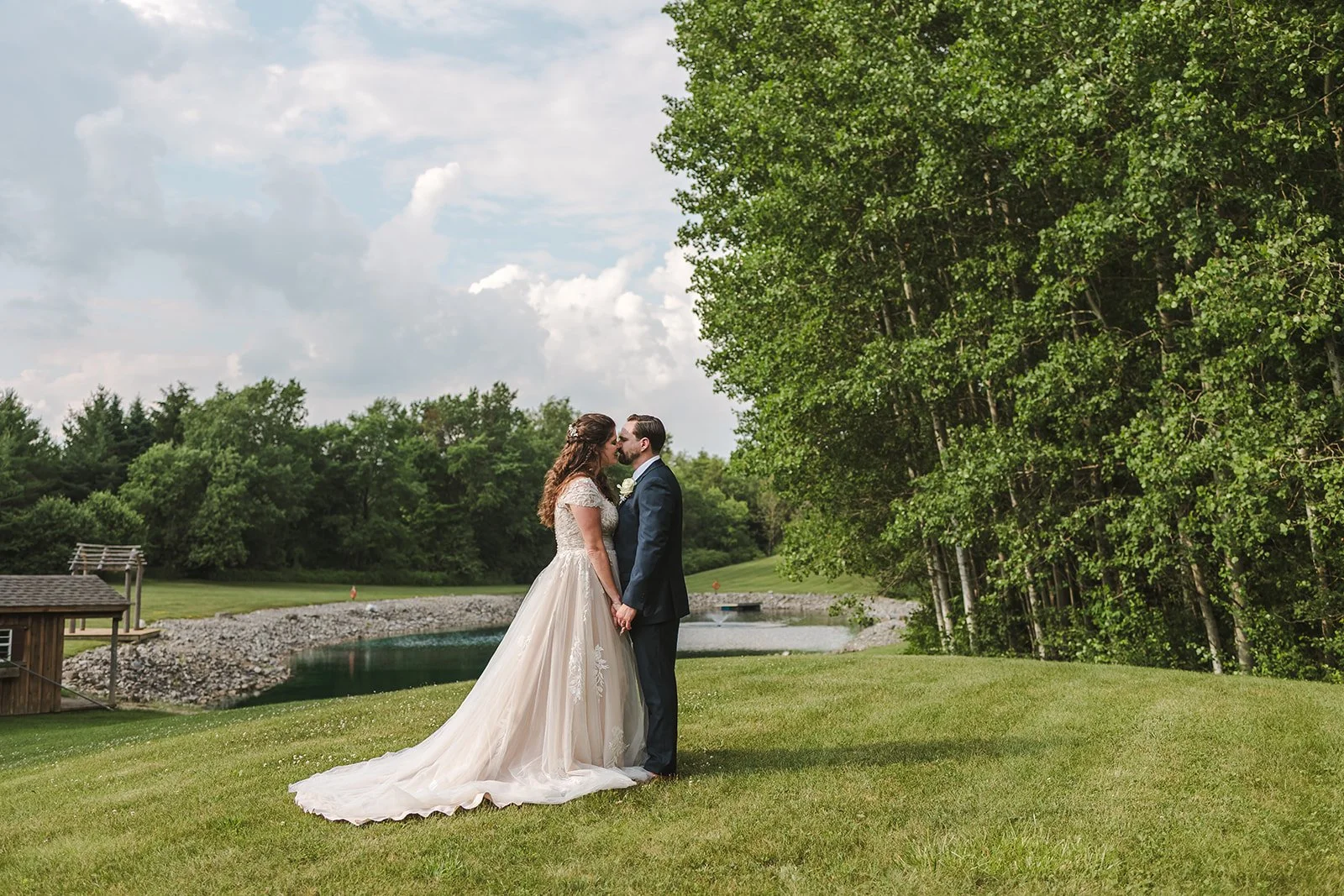 Bride and groom kiss beside pond  CJ Country events  Guelph, ON  Fedora Media.jpg